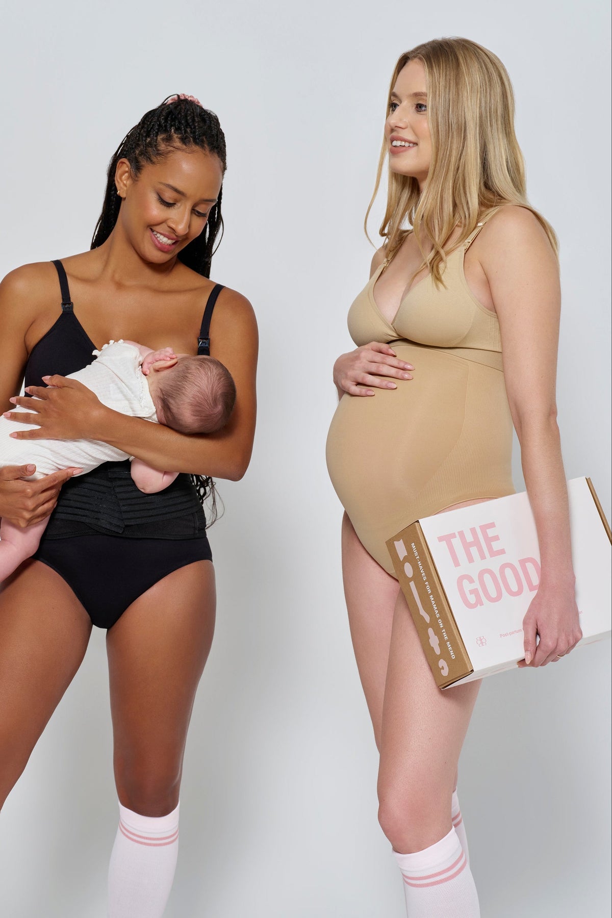 Two women model postpartum apparel; one holds a baby while the other holds The Goods care package