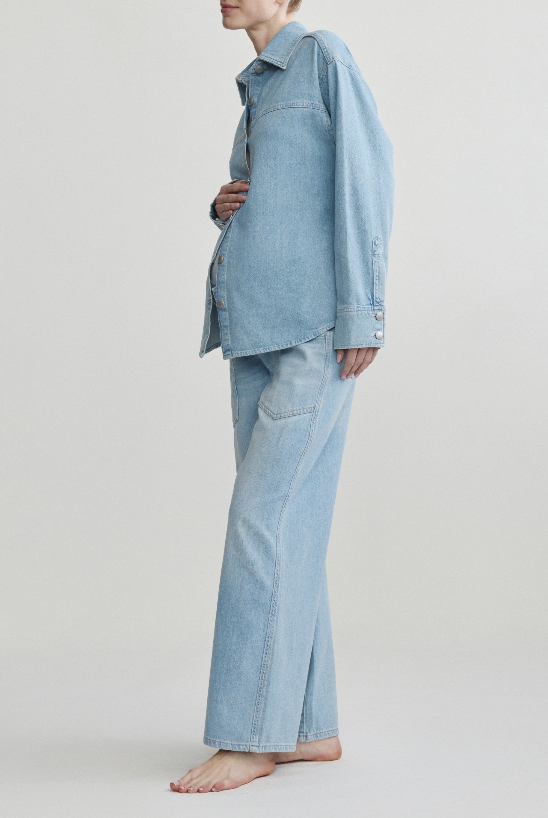 Person wearing a light blue denim outfit on a plain background