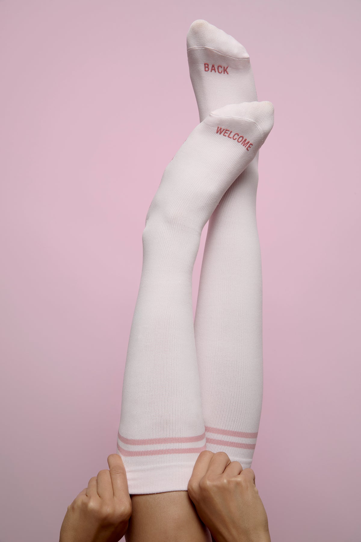 White knee-high socks with pink text on a pink background