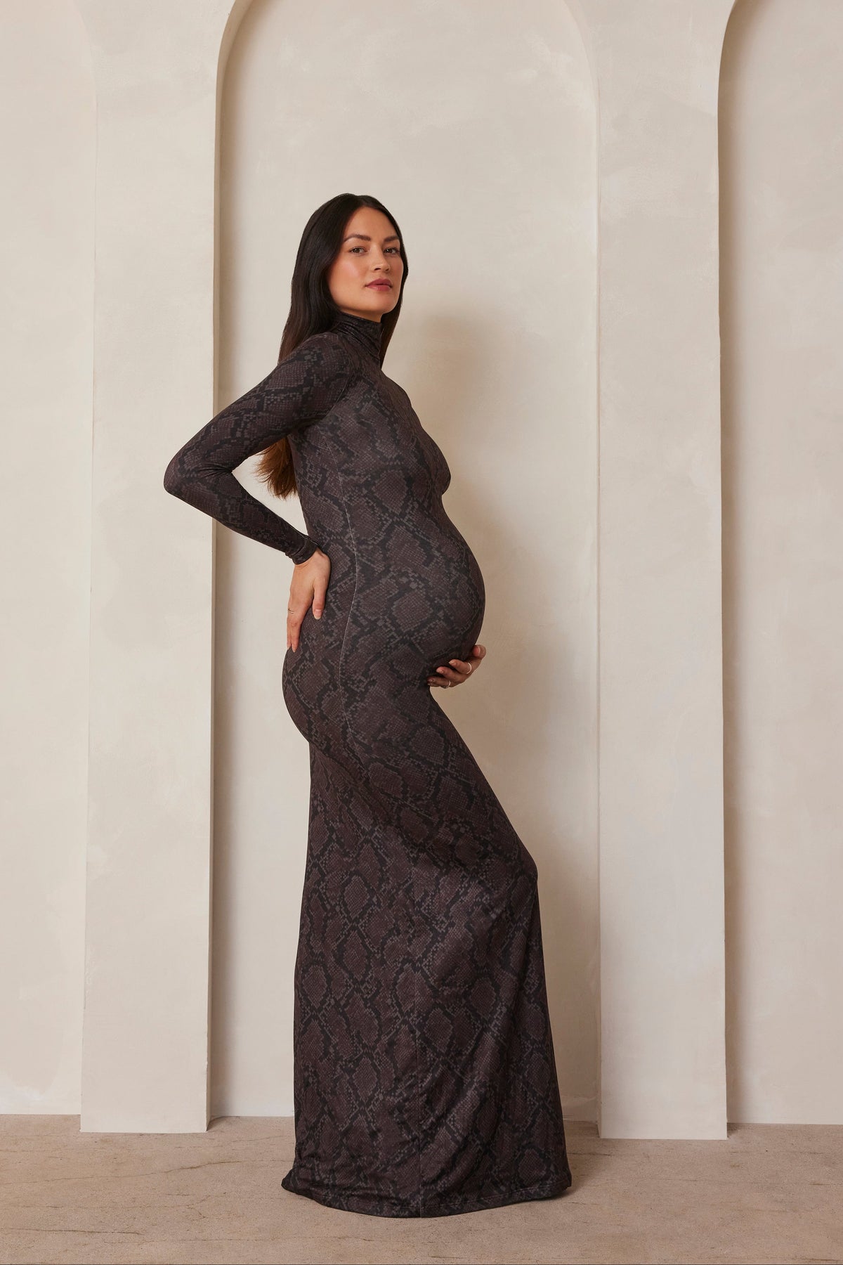Pregnant model wearing a turtleneck long sleeve maxi dress in a snake print