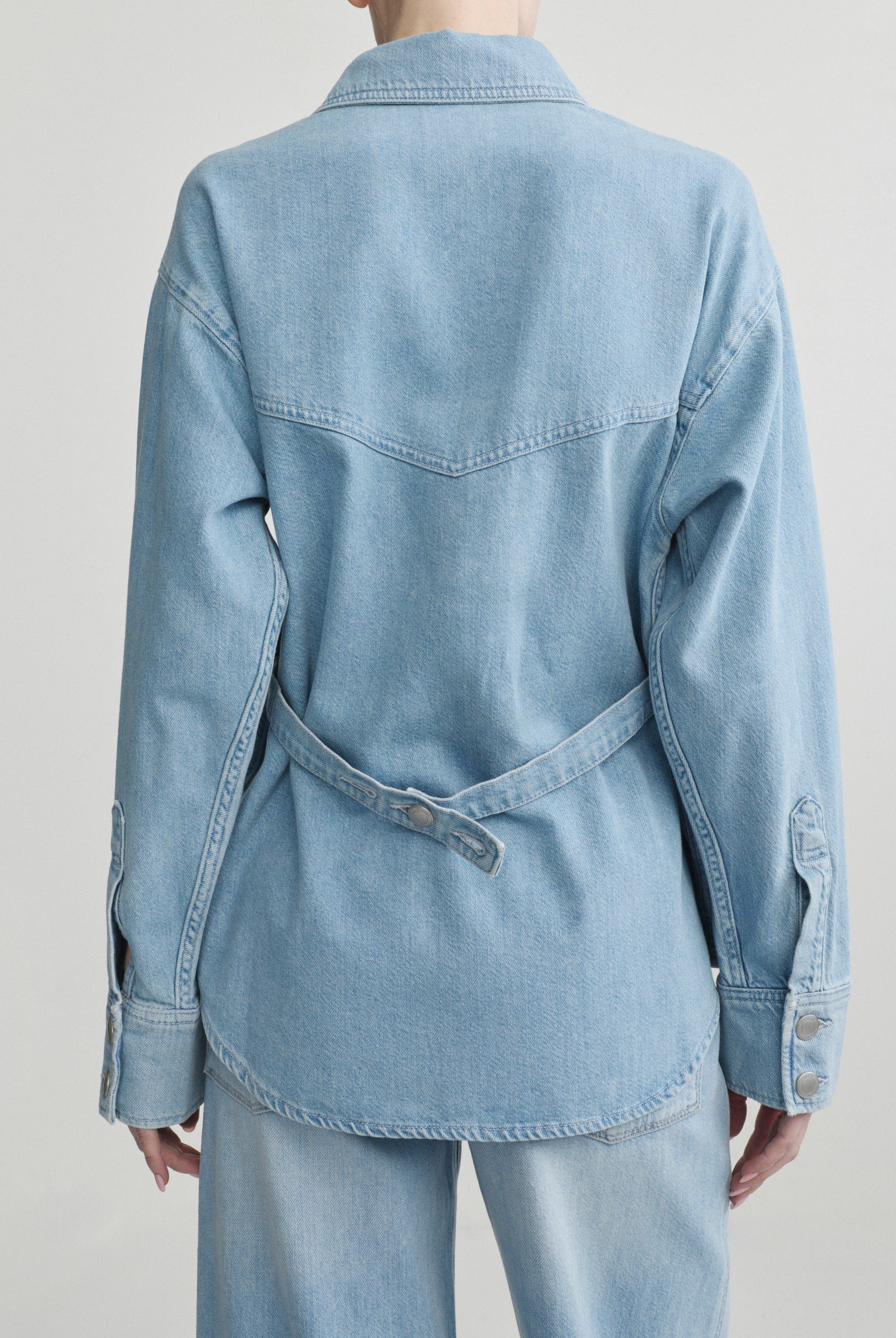 Light blue denim jacket worn by a person on a plain background