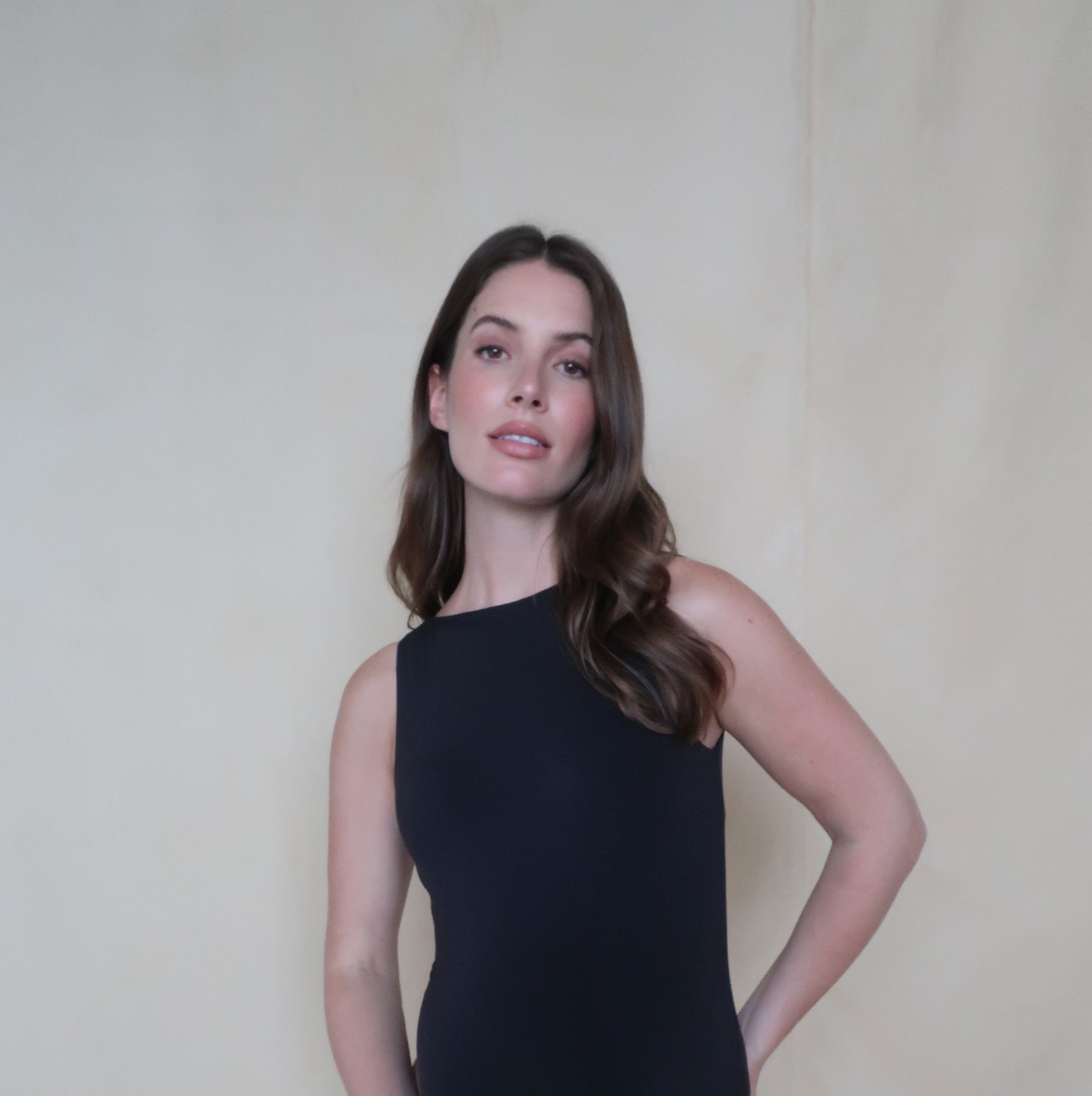 pregnant women wearing a black bumpsuit boat neck bodysuit against a black background