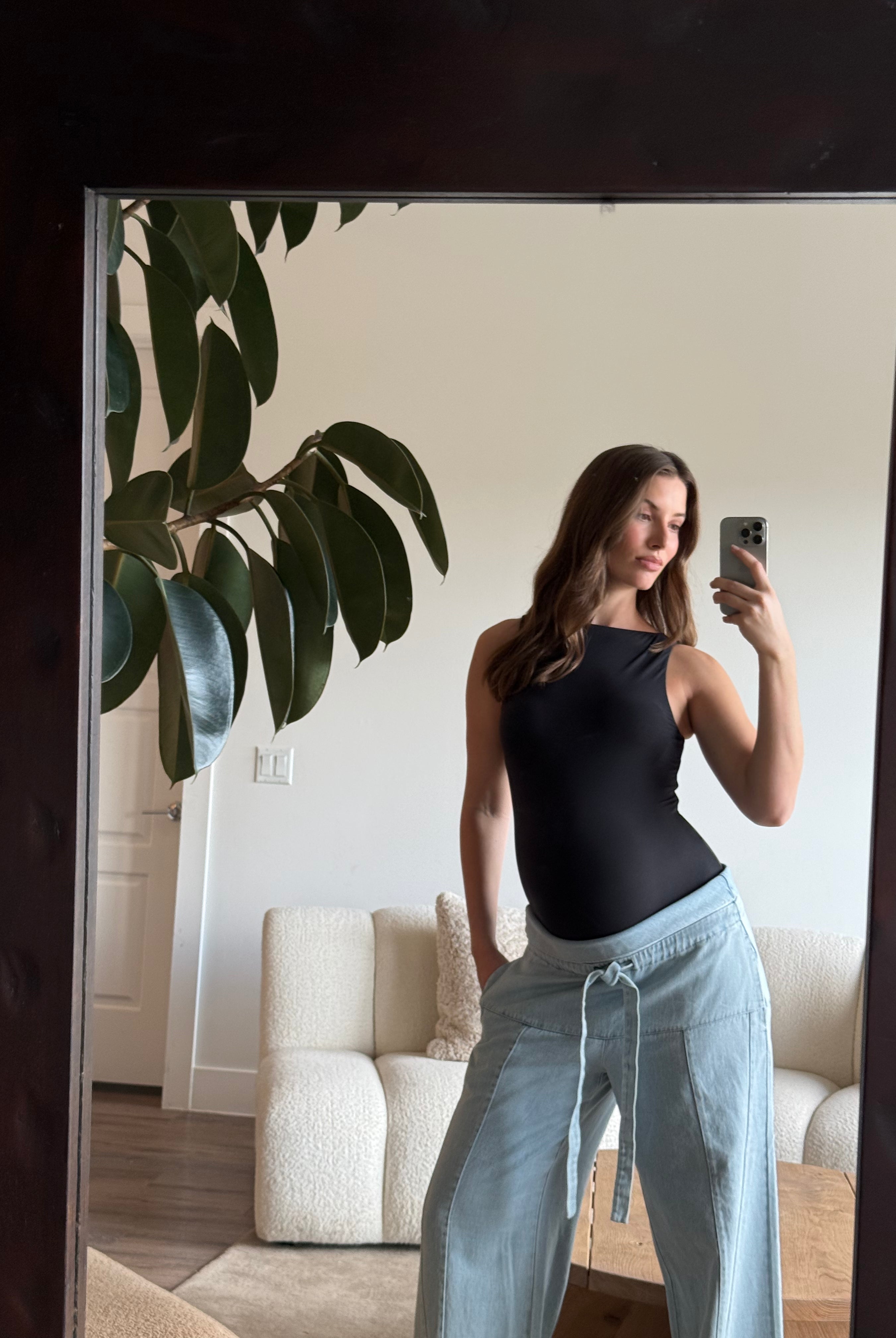 pregnant person taking a mirror selfie wearing Bumpsuitsblack boatneck bodysuit and jeans