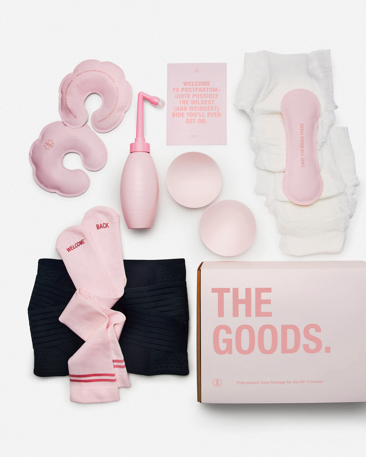 Overhead view of THE GOODS postpartum care package with pink and black recovery essentials on a white background