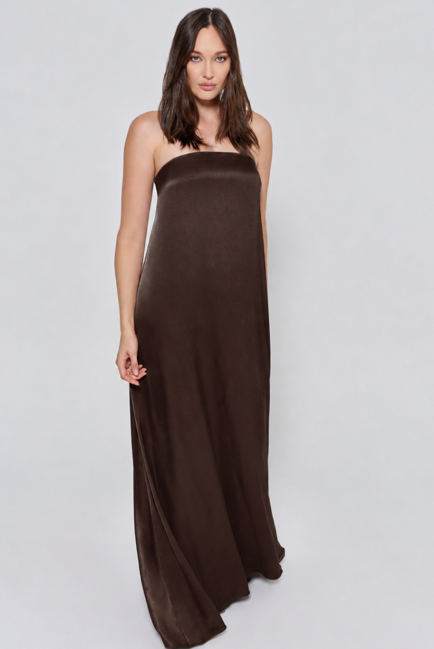 Pregnant woman wearing a Bumpsuit brushed satin gown in a chocolate color against a white background