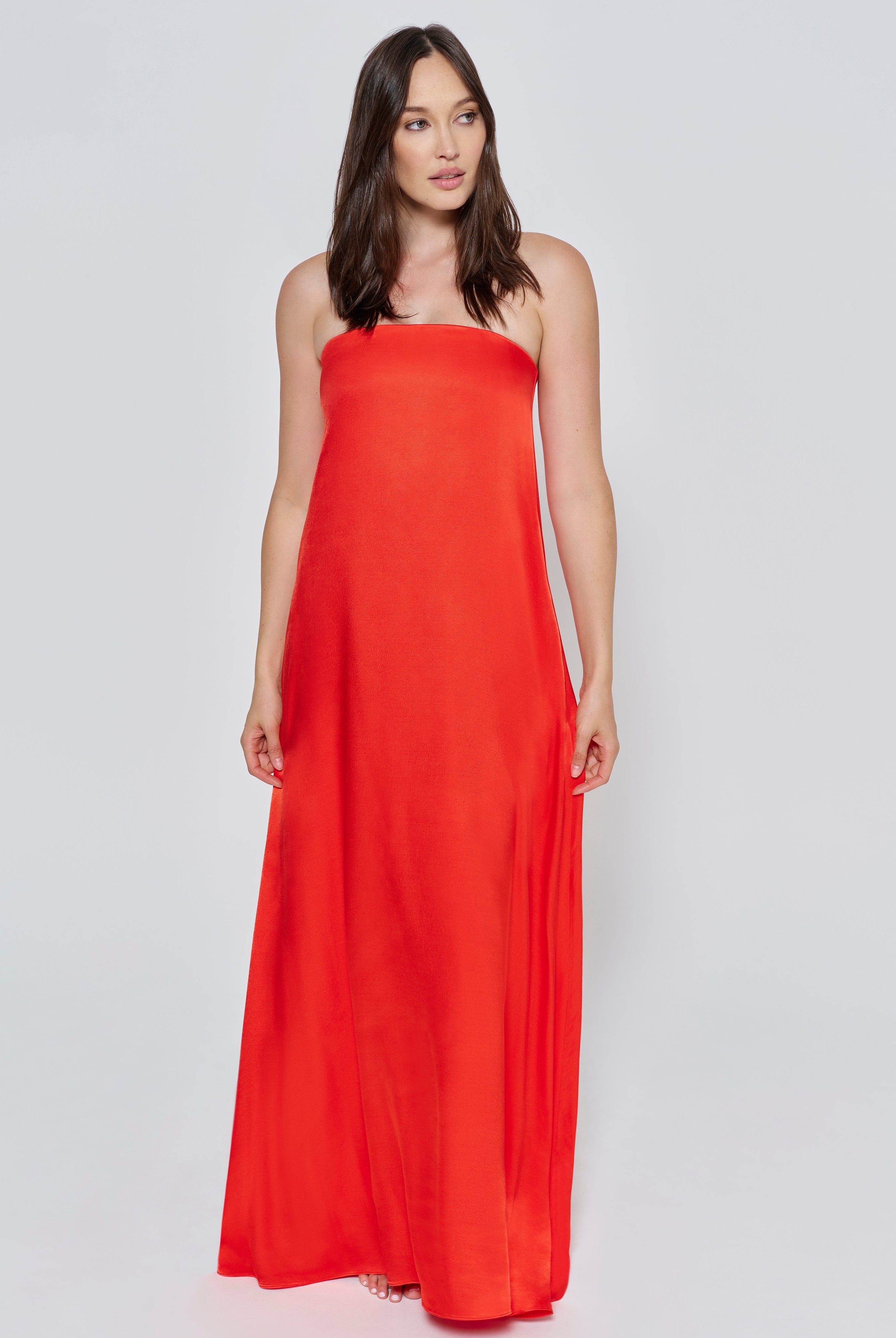 A woman wearing the Bumpsuit brushed satin strapless maxi maternity gown in red against a white background