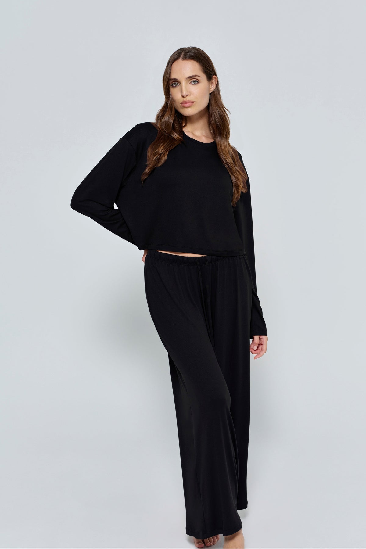 Front view of The Cloud Pant showcasing its black wide-leg fit and elastic waistband on a model against a gray background