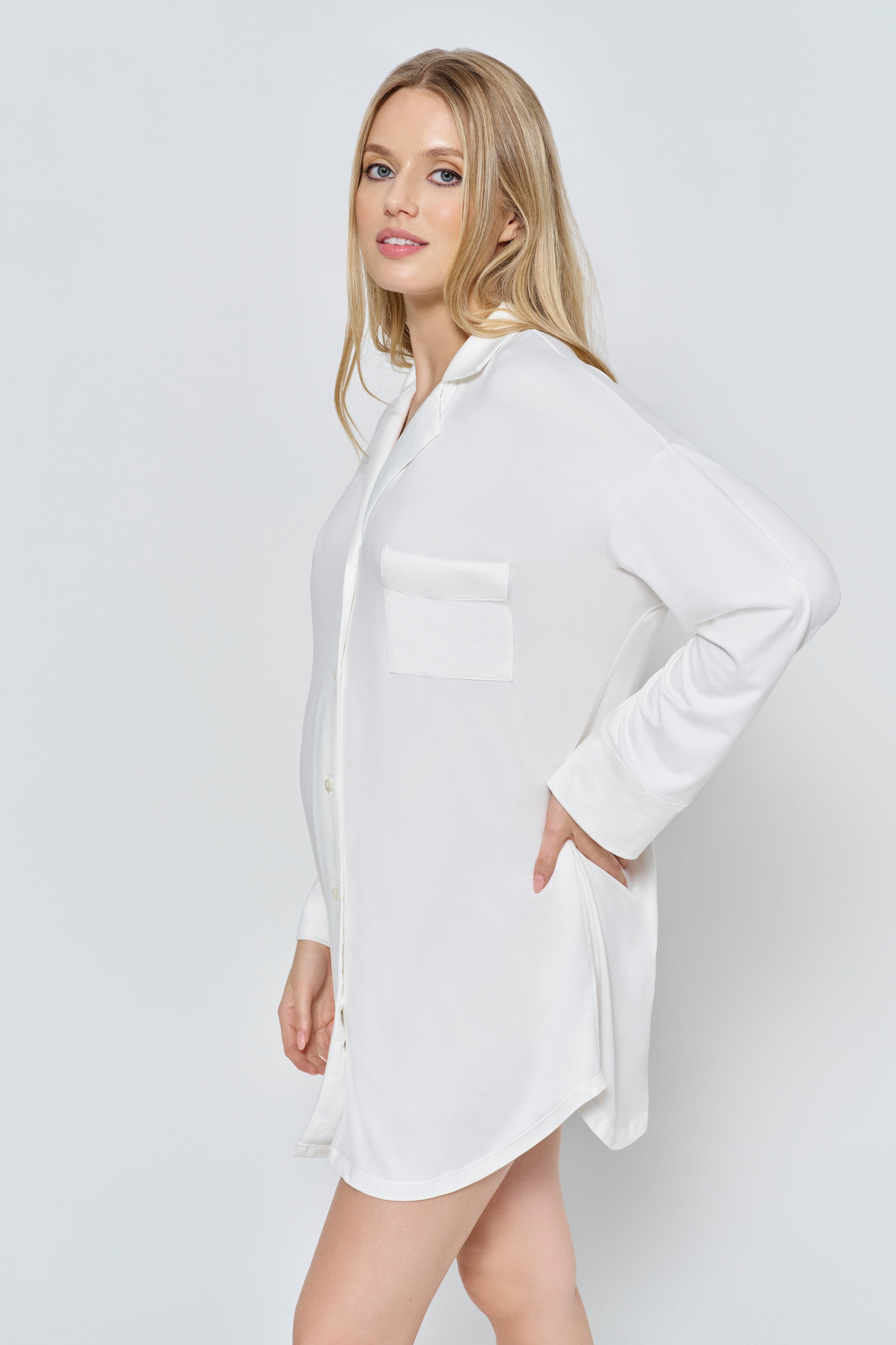 Pregnant wearing the Bumpsuit Cloud Pajama dress in ivory against a white background