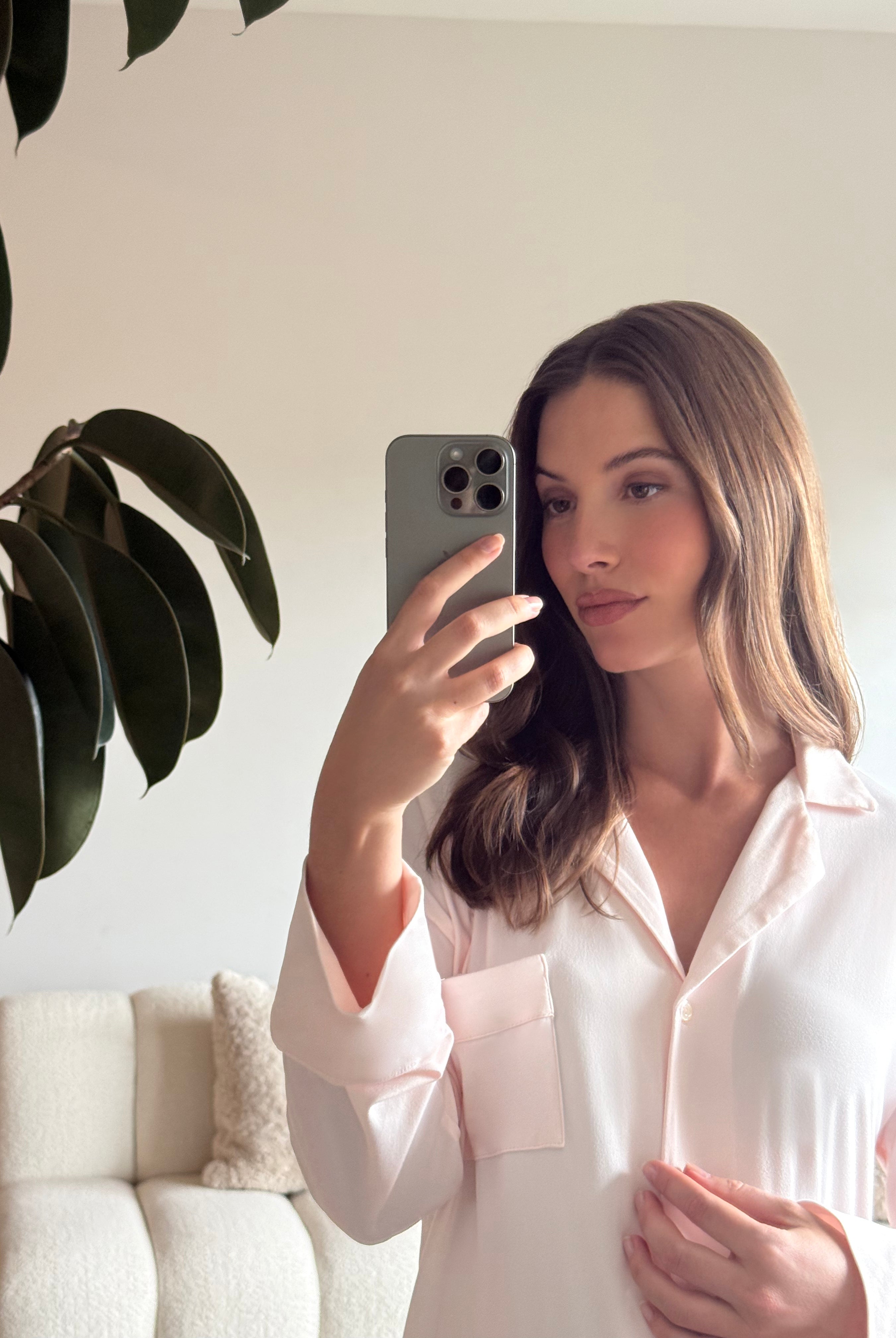 Pregnant woman taking a mirror selfie wearing a Bumpsuit Cloud ice pink pyjama dress