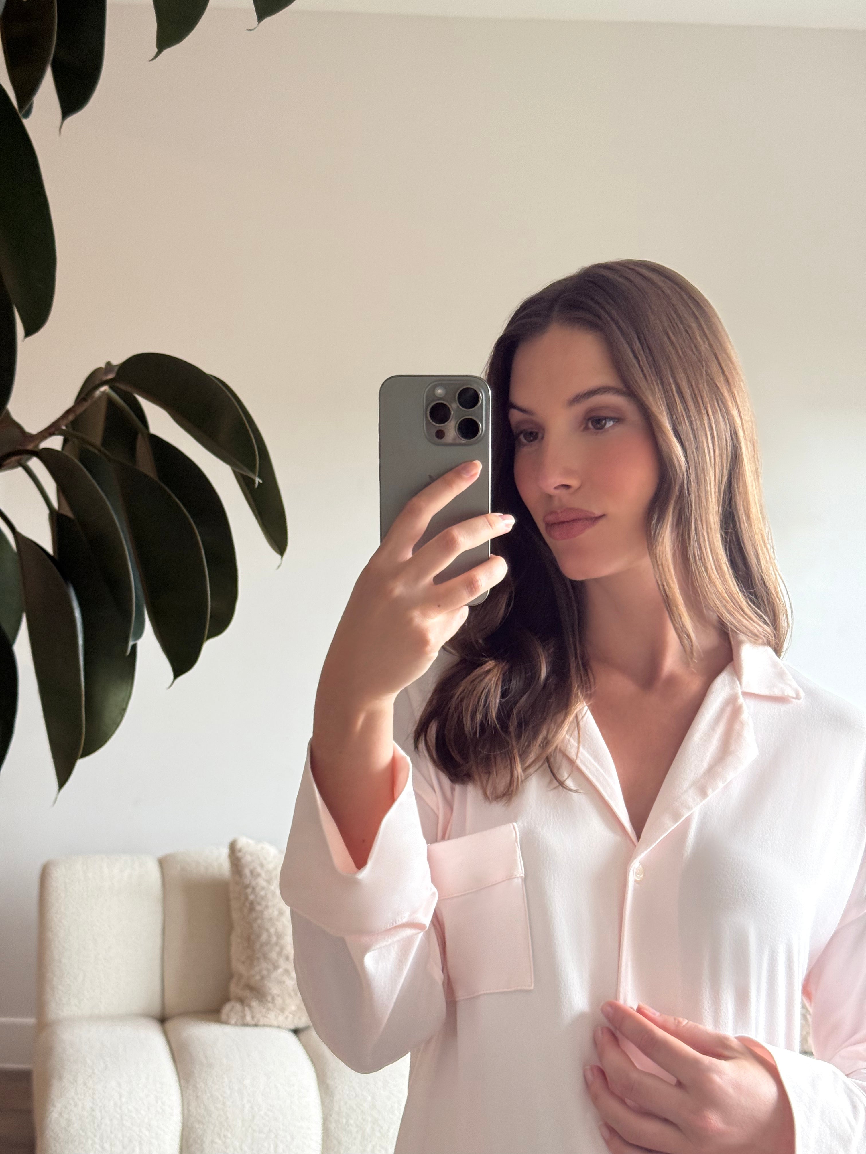 Pregnant woman taking a mirror selfie wearing a Bumpsuit Cloud ice pink pyjama dress