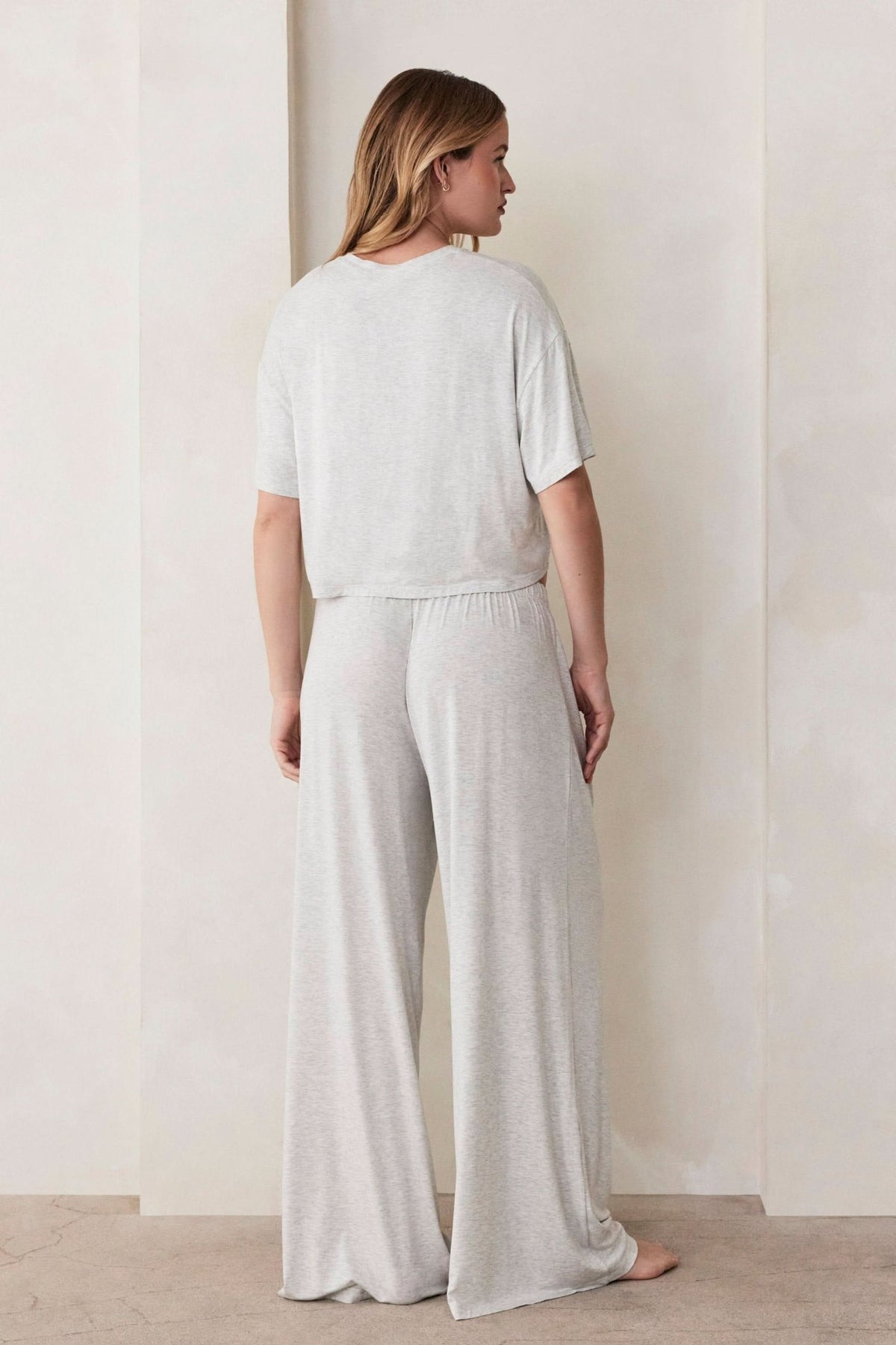 Back view of The Cotton Cloud Pant showcasing heather grey wide-leg fit and elastic waistband against a plain wall