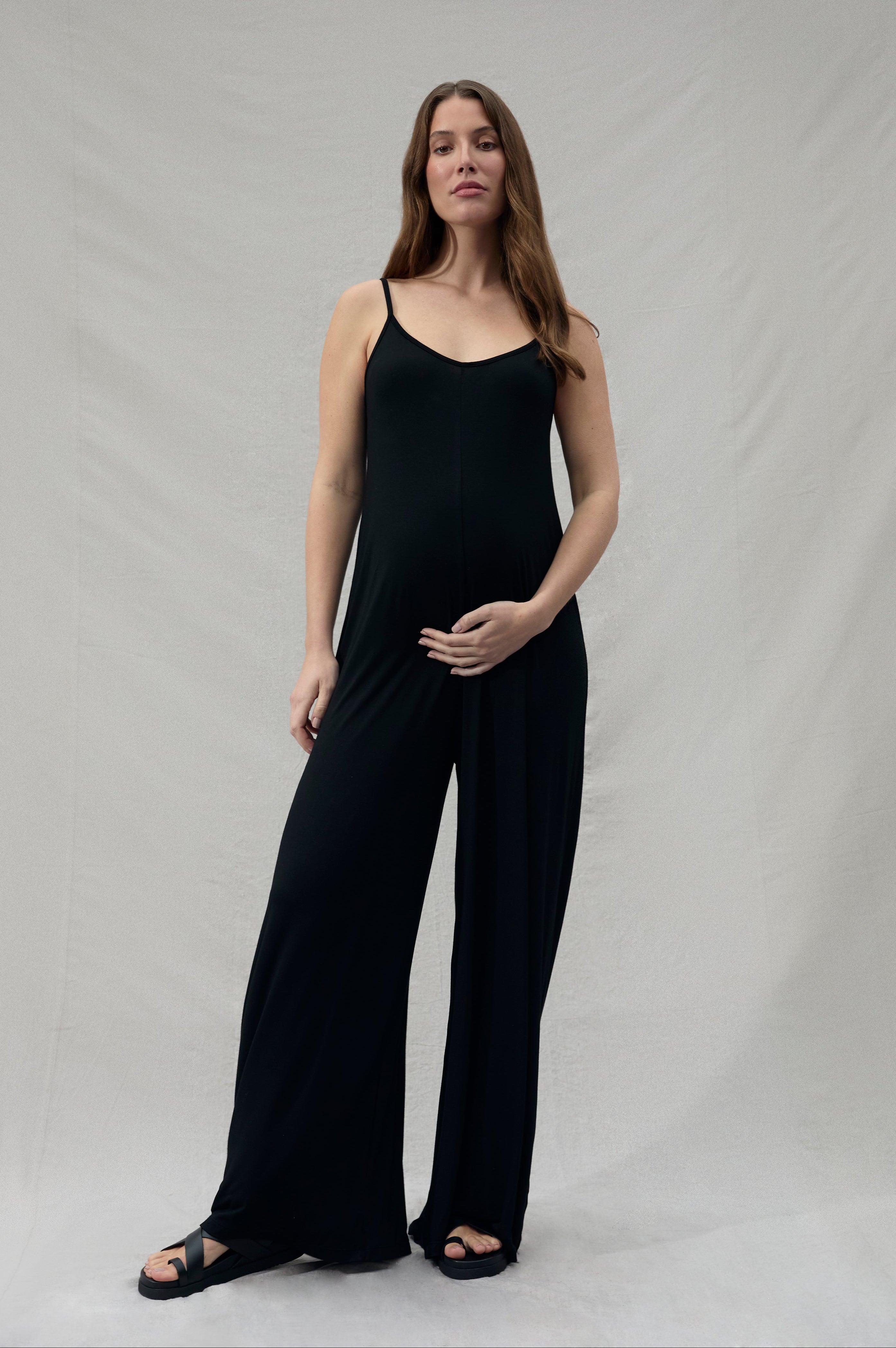 pregnant woman wearing a black cotton jumpsuit holding under her belly