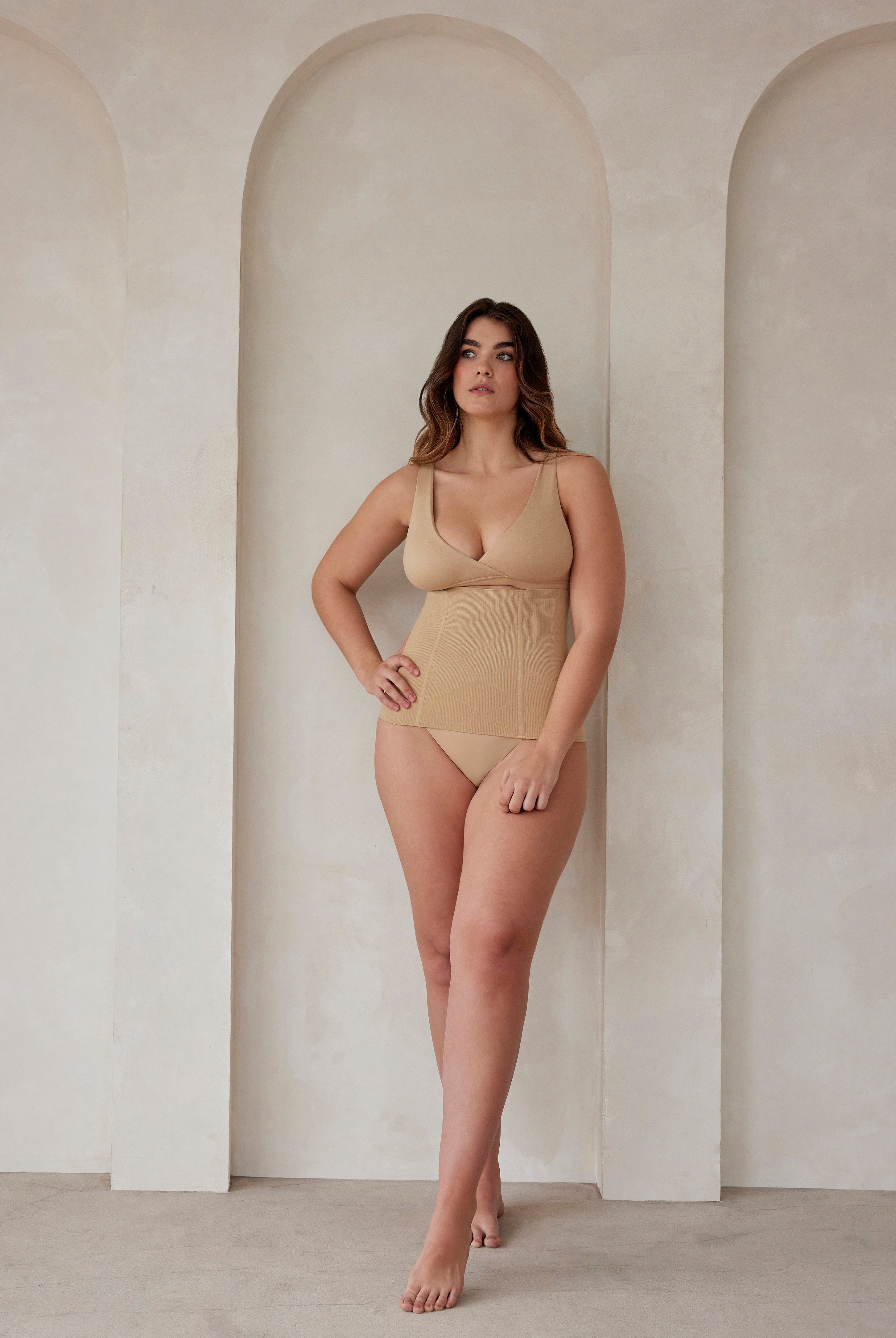 A woman wearing a beige reversible comfy bra and support waist trainer by Bumpsuit