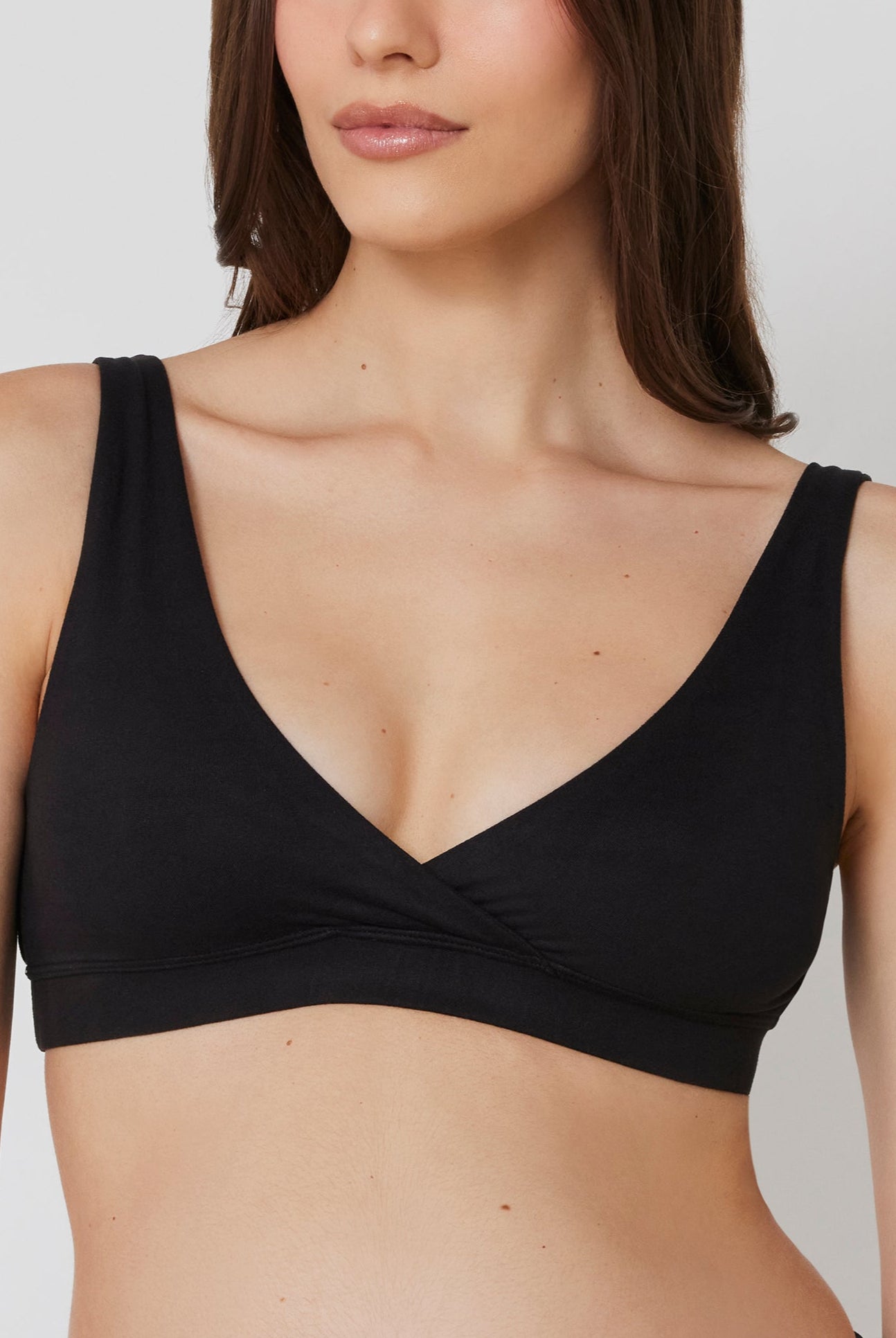 Woman wearing a black reversible comfy bra on a white background