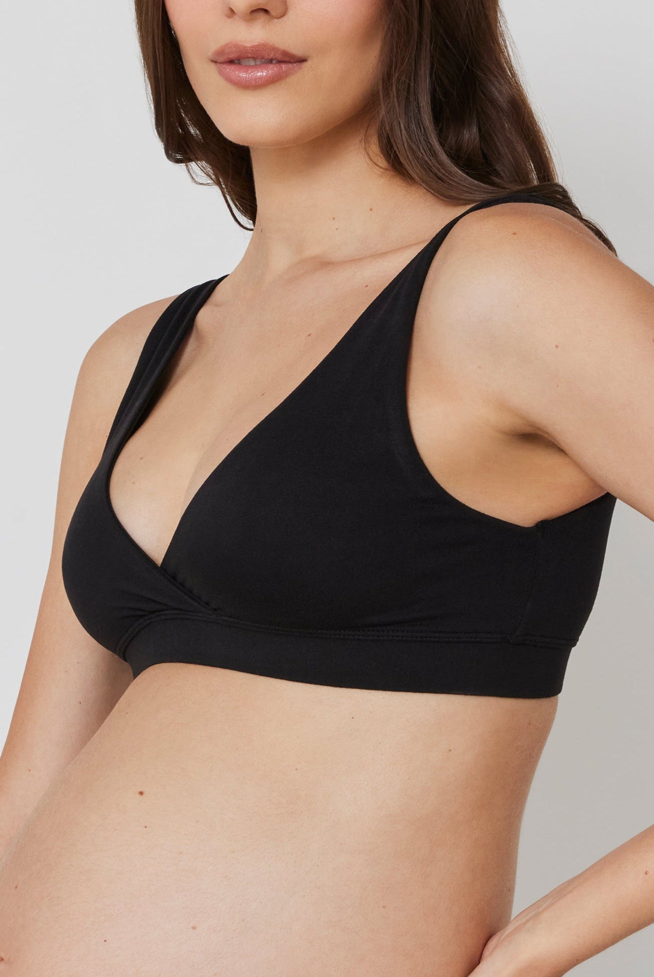 Pregnant woman wearing a black reversible comfy bra in black on a white background