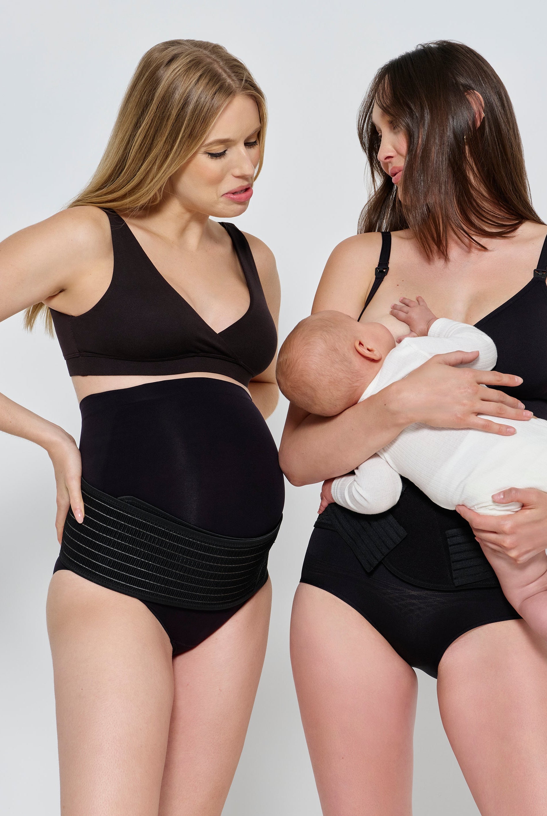 Two women wearing black maternity wear holding a baby.