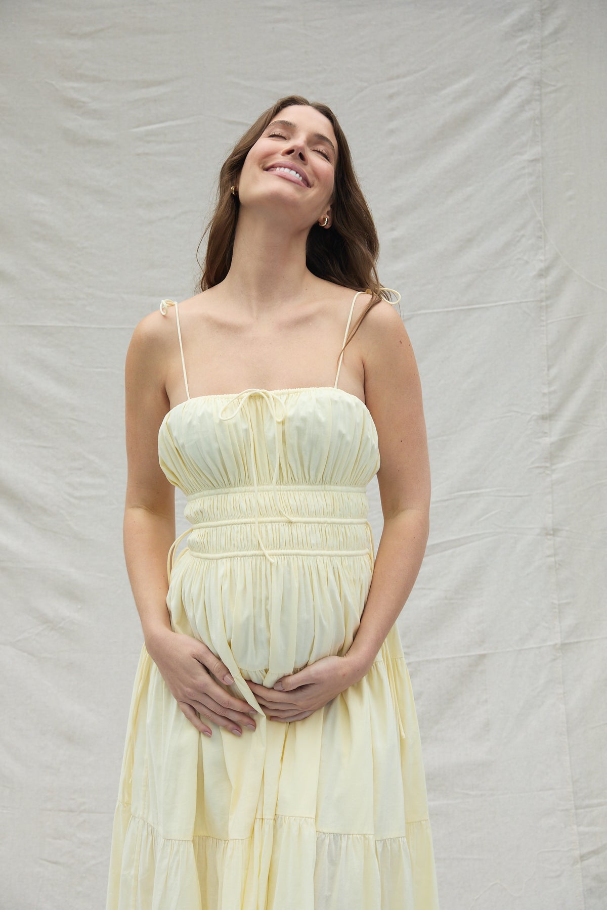 Woman wearing a light yellow dress against a plain background