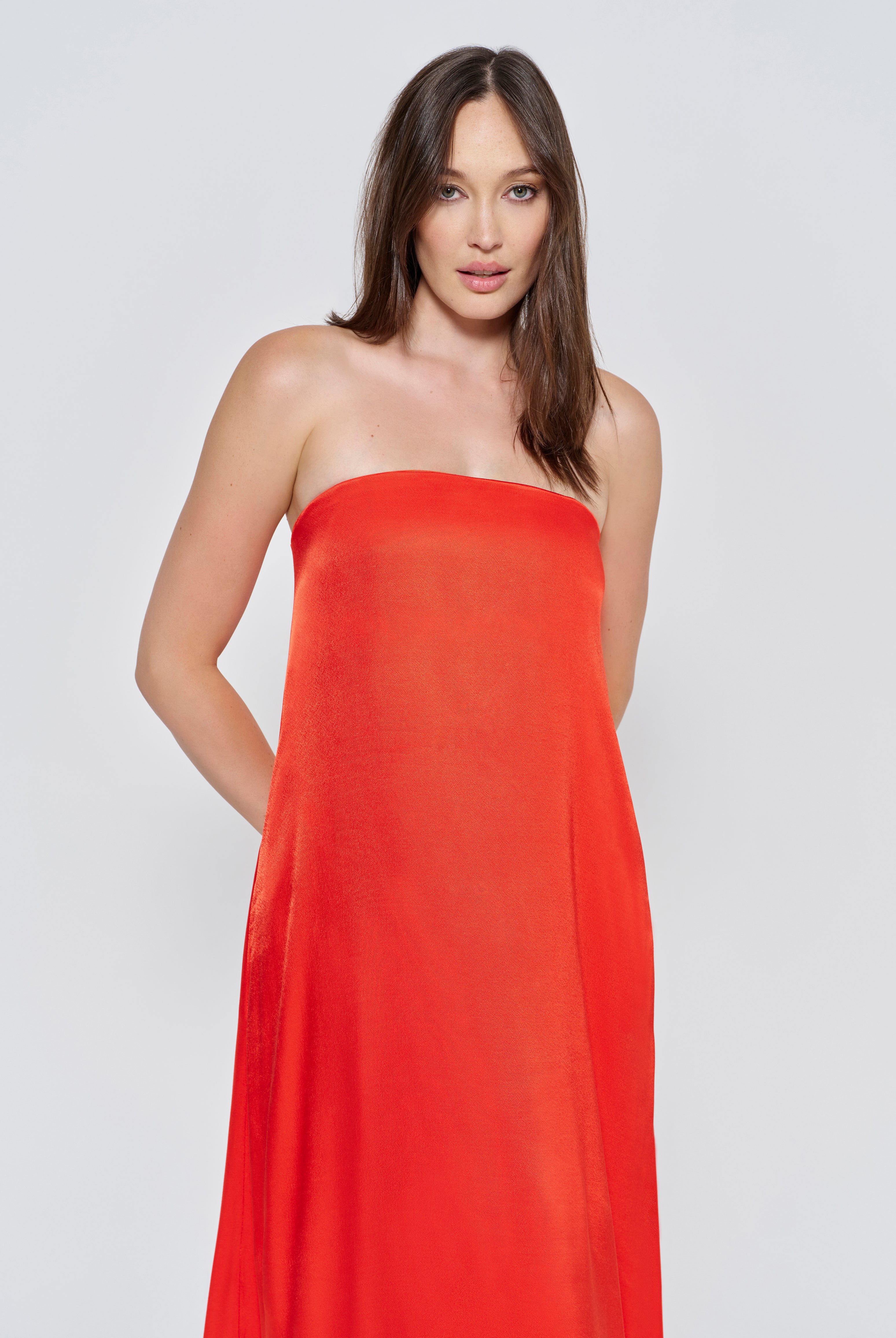 A woman wearing the Bumpsuit brushed satin strapless maxi maternity gown in red against a white background