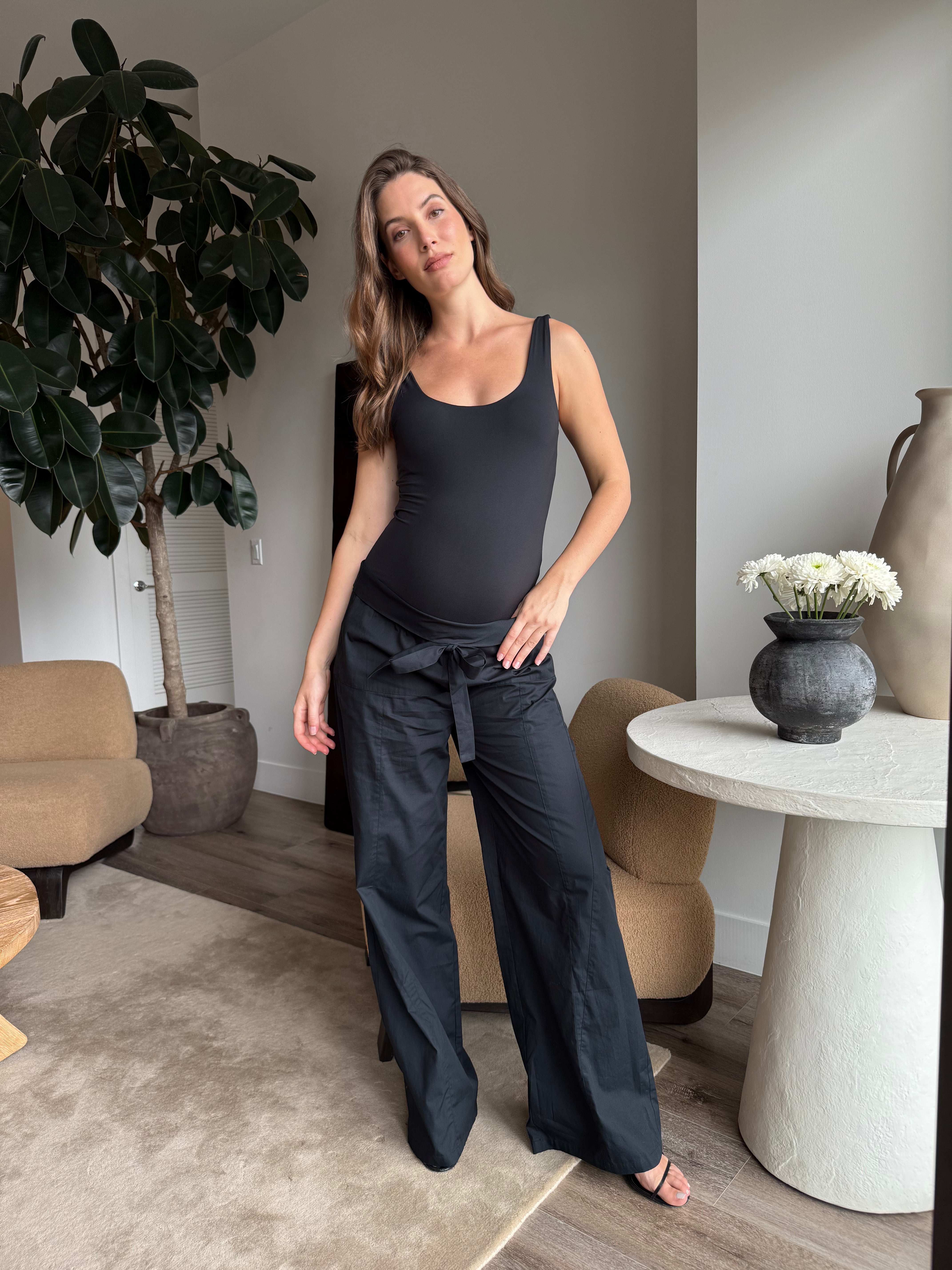 pregnant women wearing a bumpsuit black bodysuit and jeans in living room