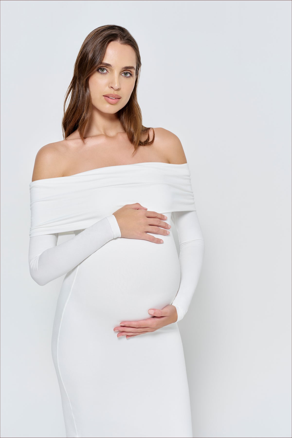 Pregnant woman wearing a ivory off-shoulder dress with long sleeves