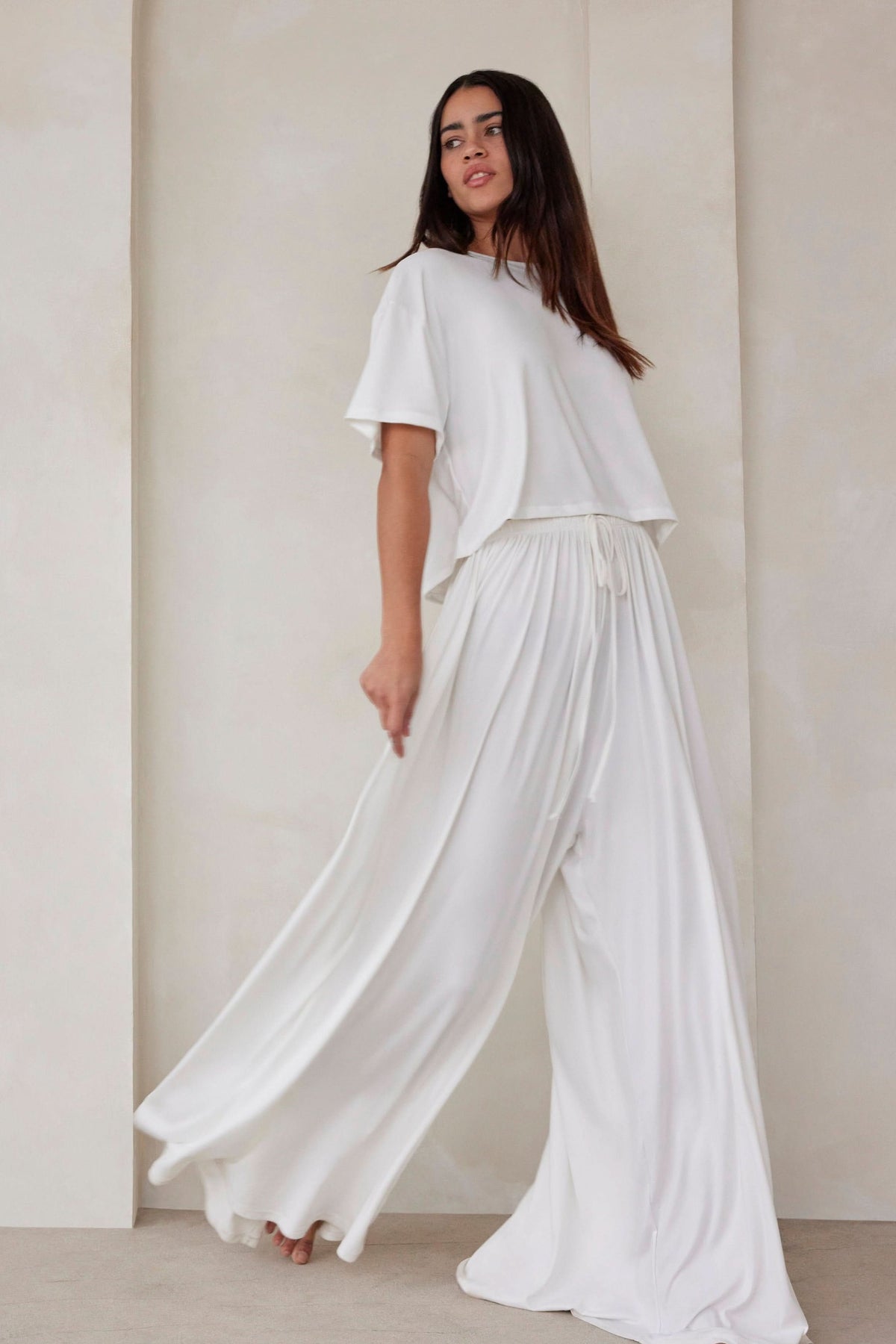 Woman wearing the Bumpsuit Maternity Cloud Short Sleeve Crop Tee and oversized Parachute pant in Ivory