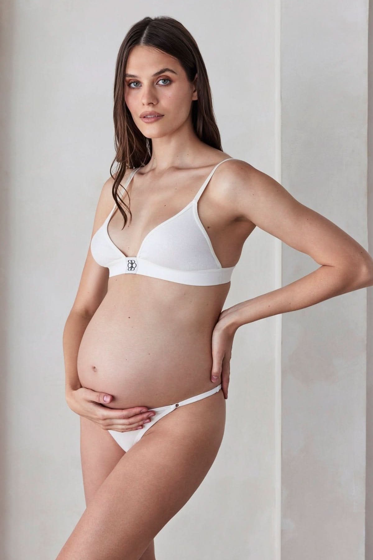 Three-quarter view of Cotton Rib Triangle Bralette showcasing white ribbed fabric and triangle cups on a pregnant model in a neutral interior