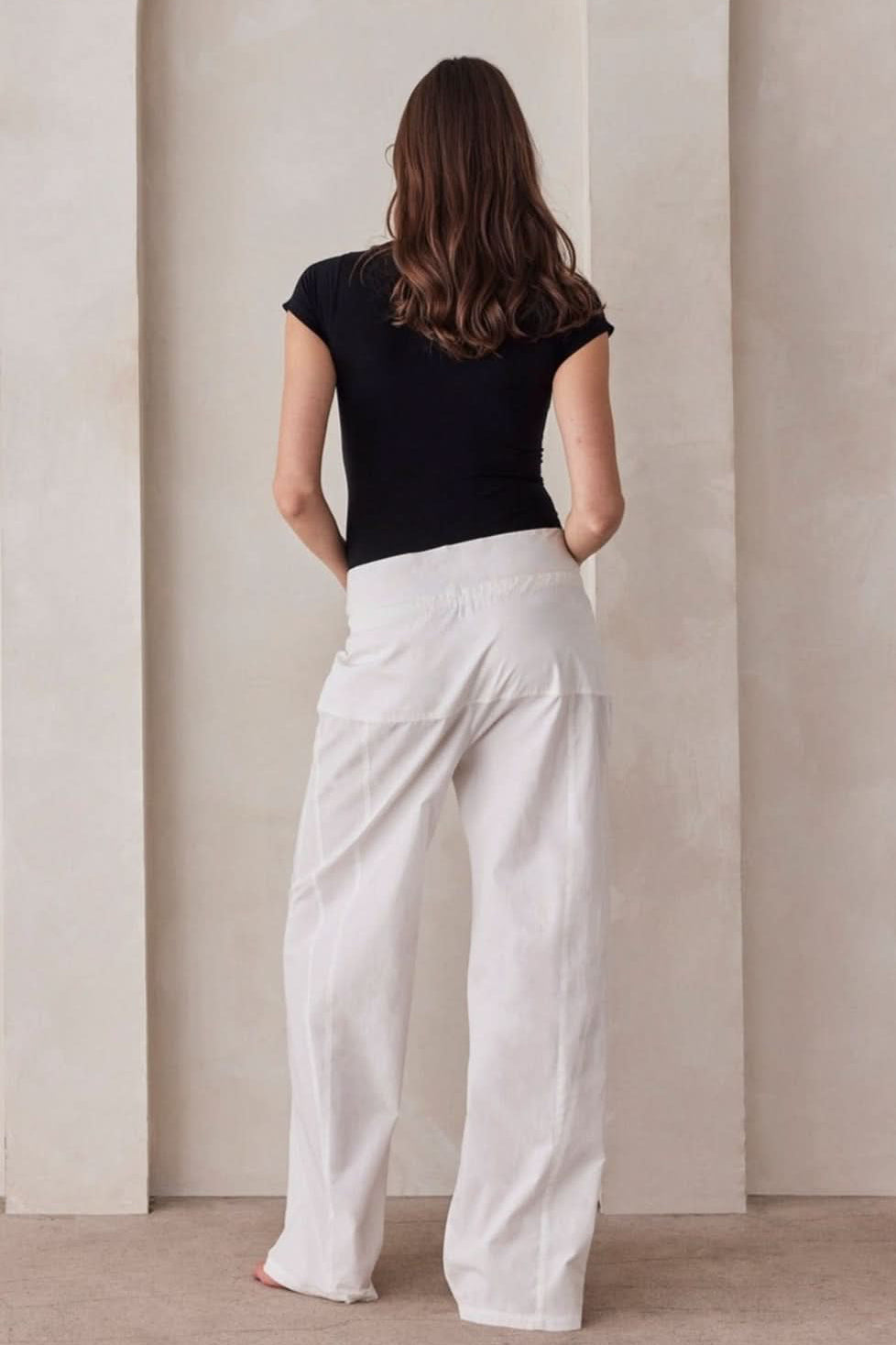 Rear view of white poplin relaxed pant showcasing the foldable waistband on a model against a neutral background