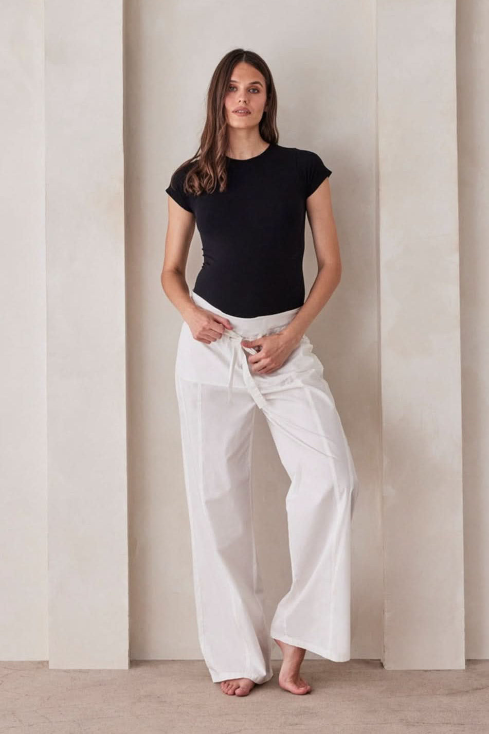 Front view of The Relaxed Pant showcasing the foldable waistband and waist tie with a beige wall background