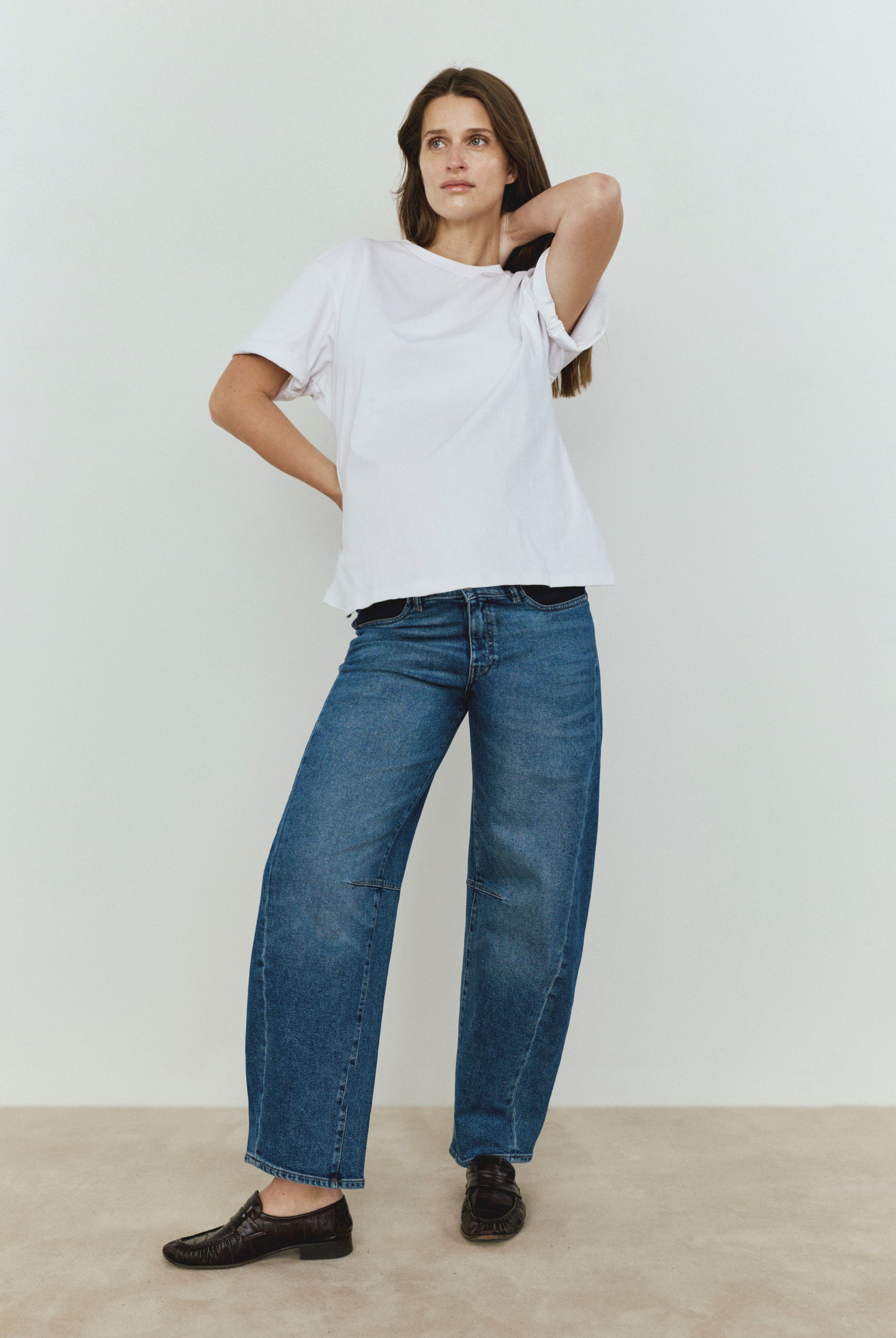 Person wearing a white t-shirt and blue jeans against a plain background