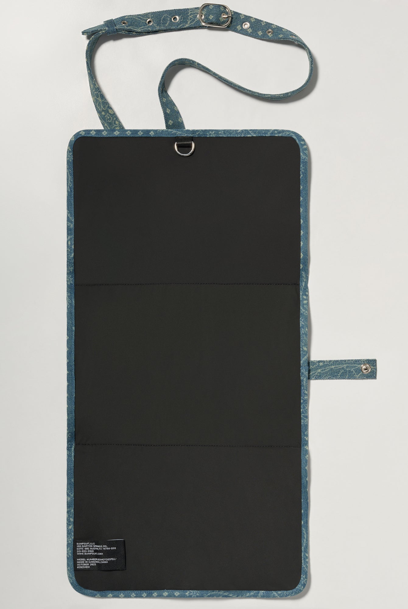 A denim roll up diaper change mat bag by Spell and Bumpsuit,, shown on a light gray background with wipes and diapers