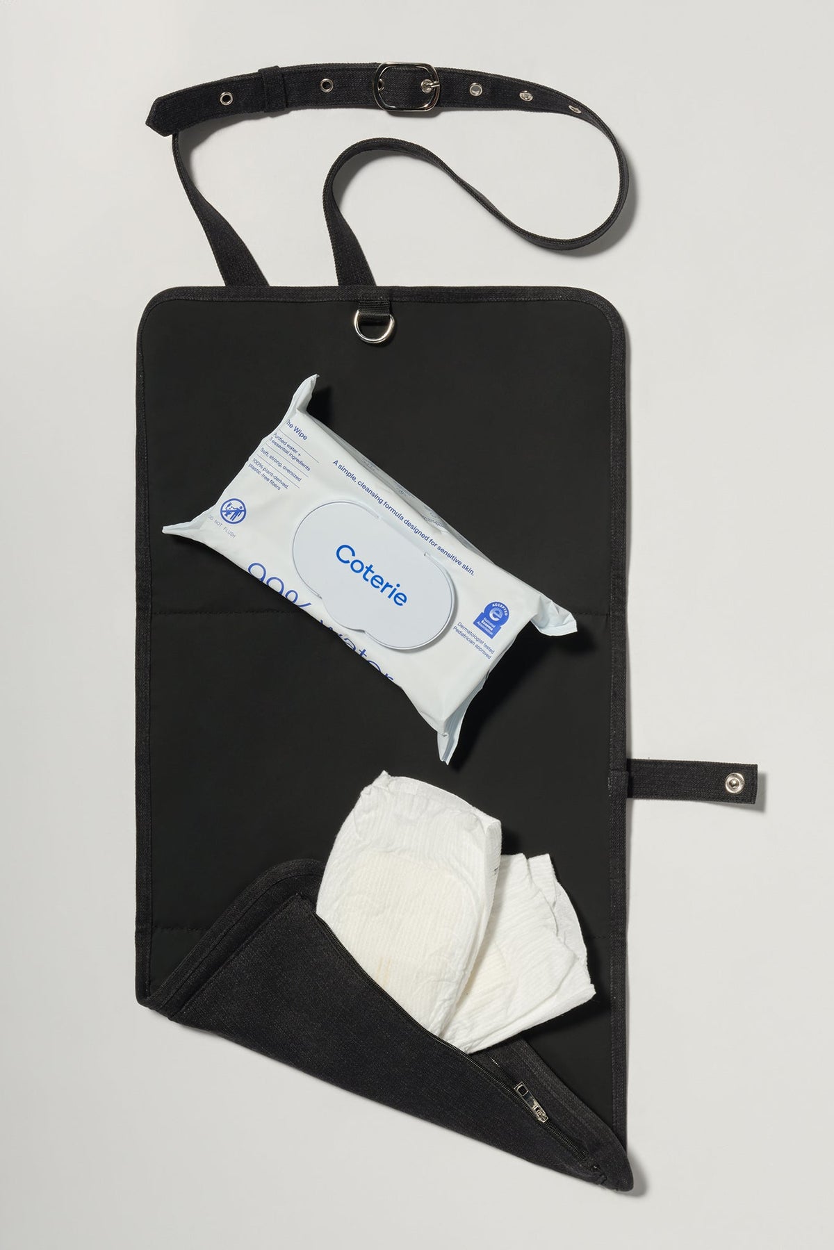 Open view of Mom-On-The-Go Bag showcasing its built-in changing mat with wipes and diapers on a light gray background
