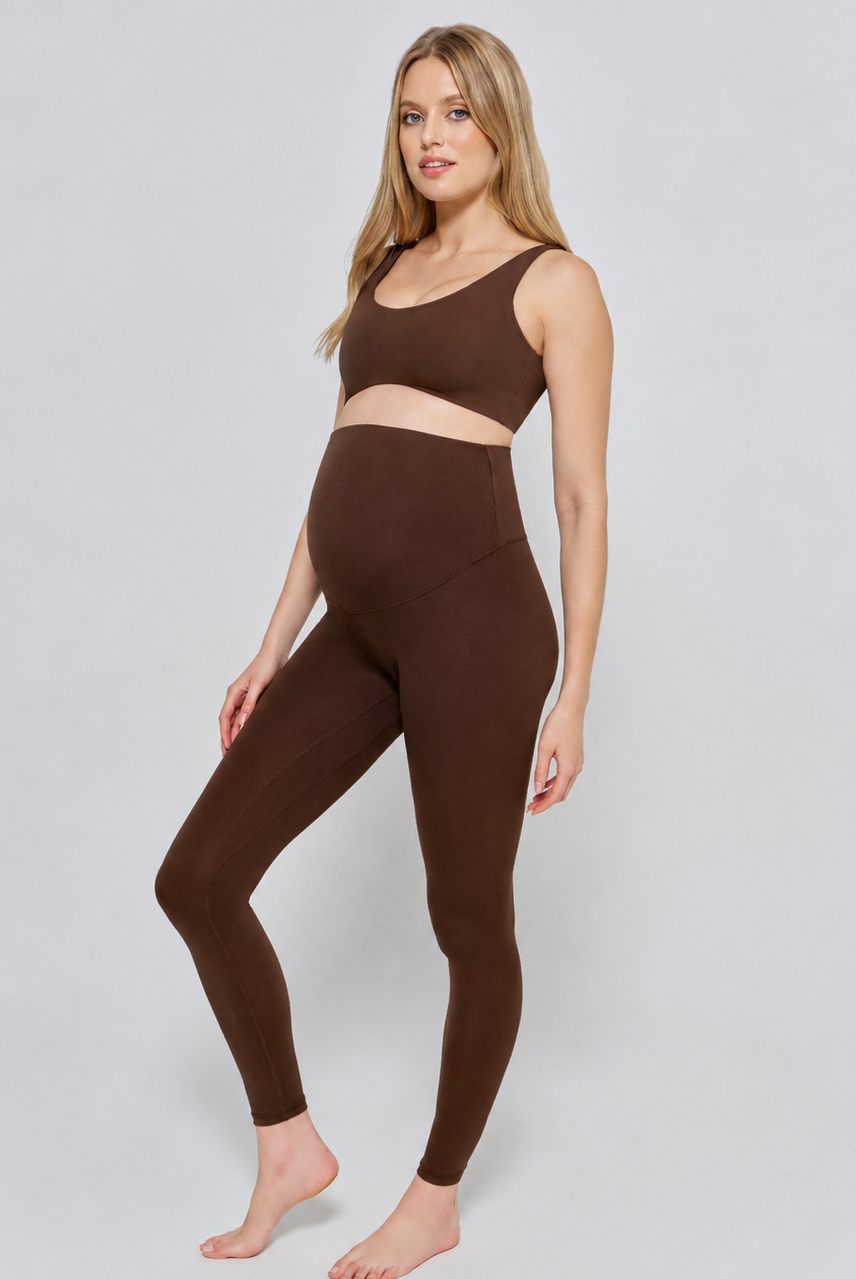 Woman wearing a bumpsuit chocolate brown athletic outfit on a white background