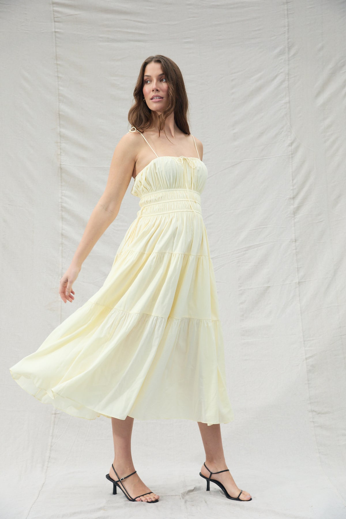 Woman wearing a light yellow dress against a plain background
