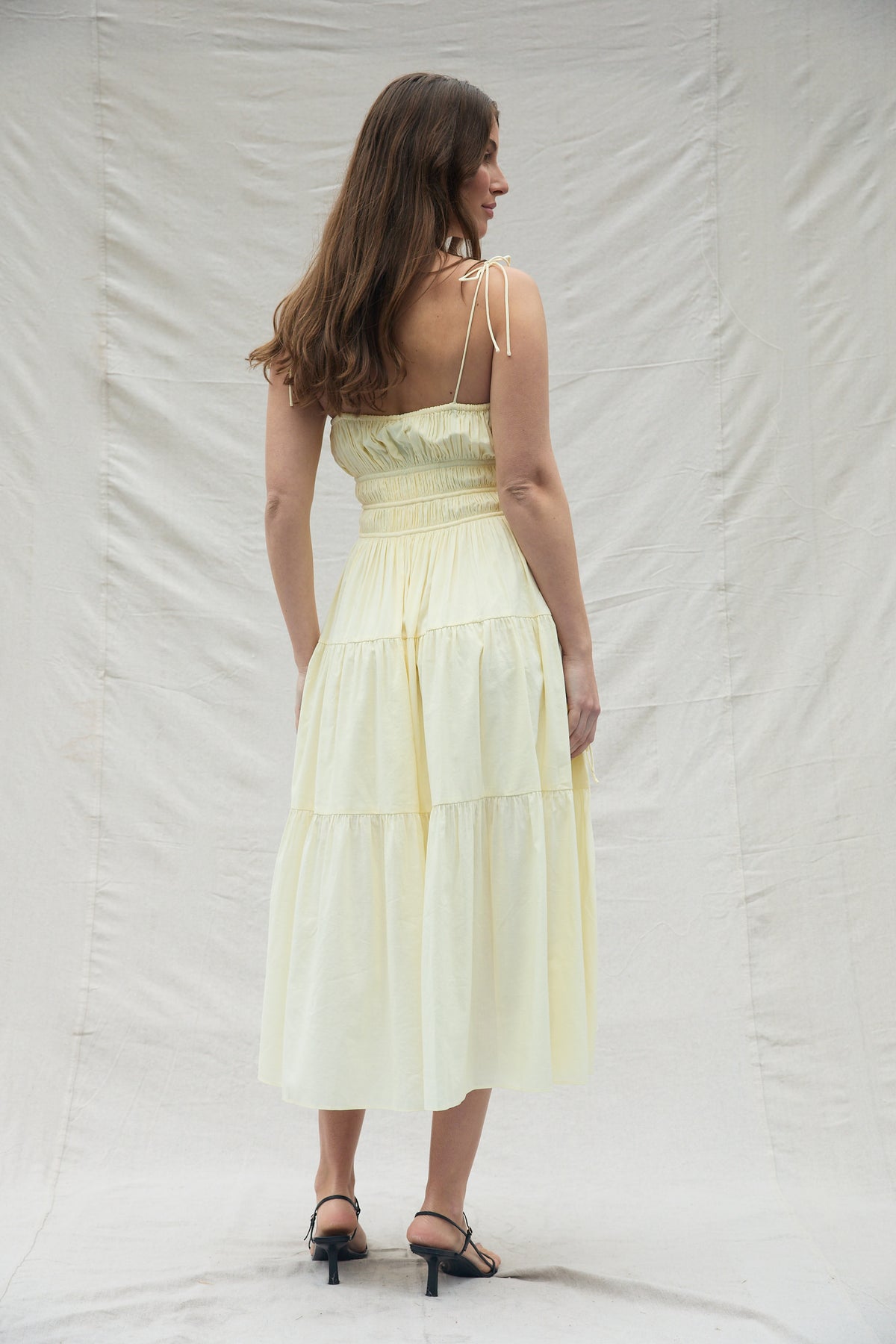 Woman wearing a light yellow dress against a white background