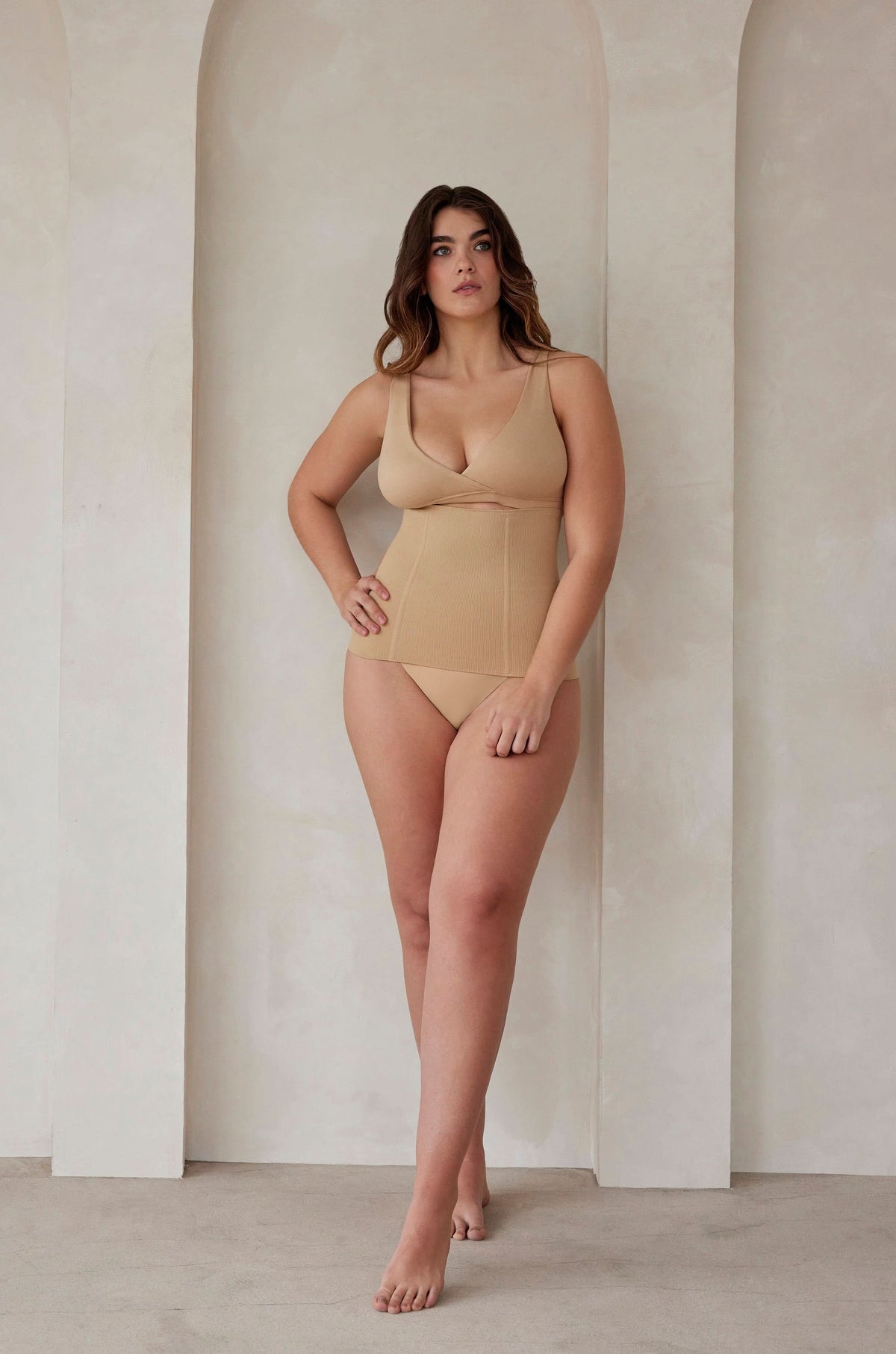 Woman wearing the postpartum support waist trainer in beige by bumpsuit