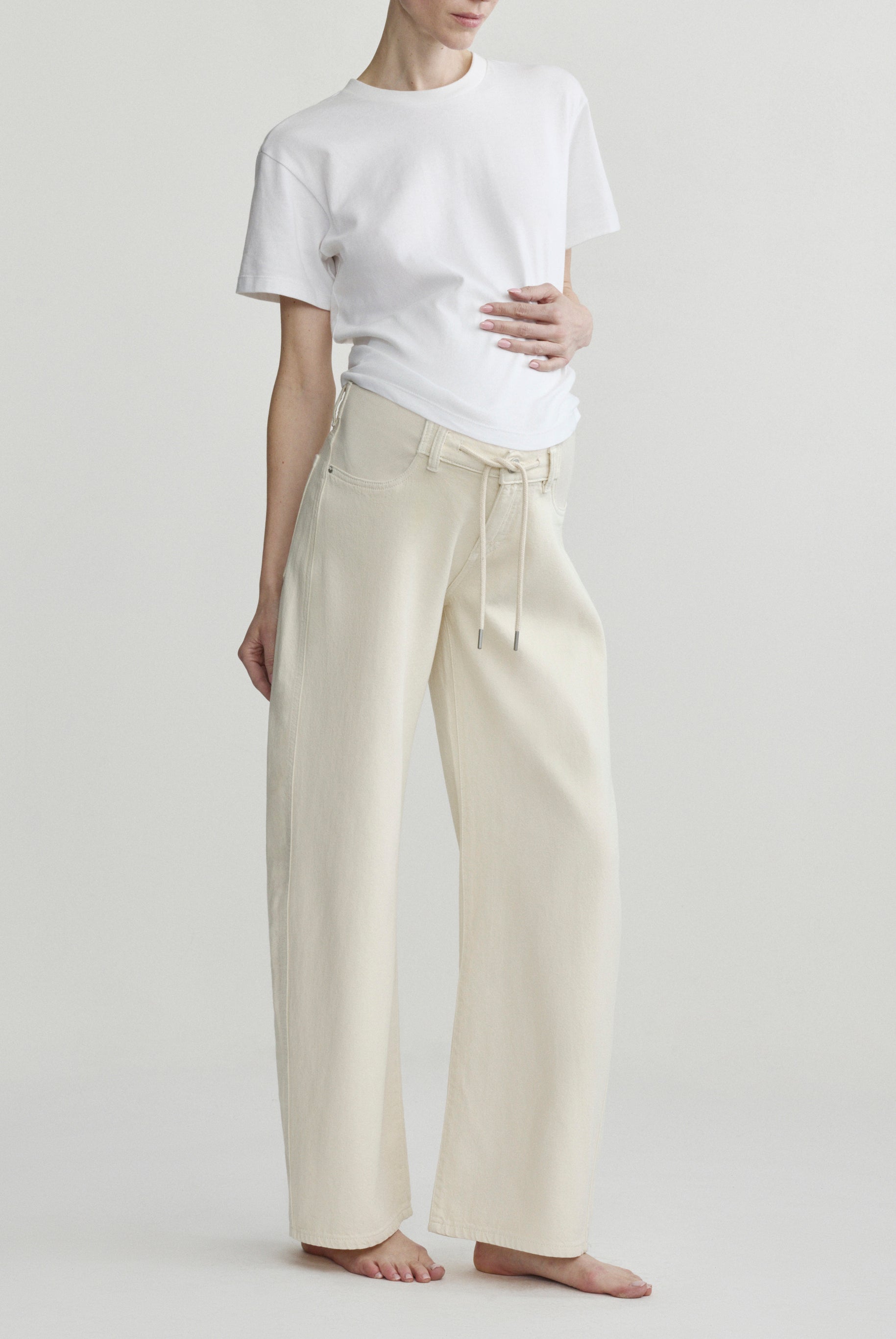 Person wearing a white t-shirt and beige pants on a plain background
