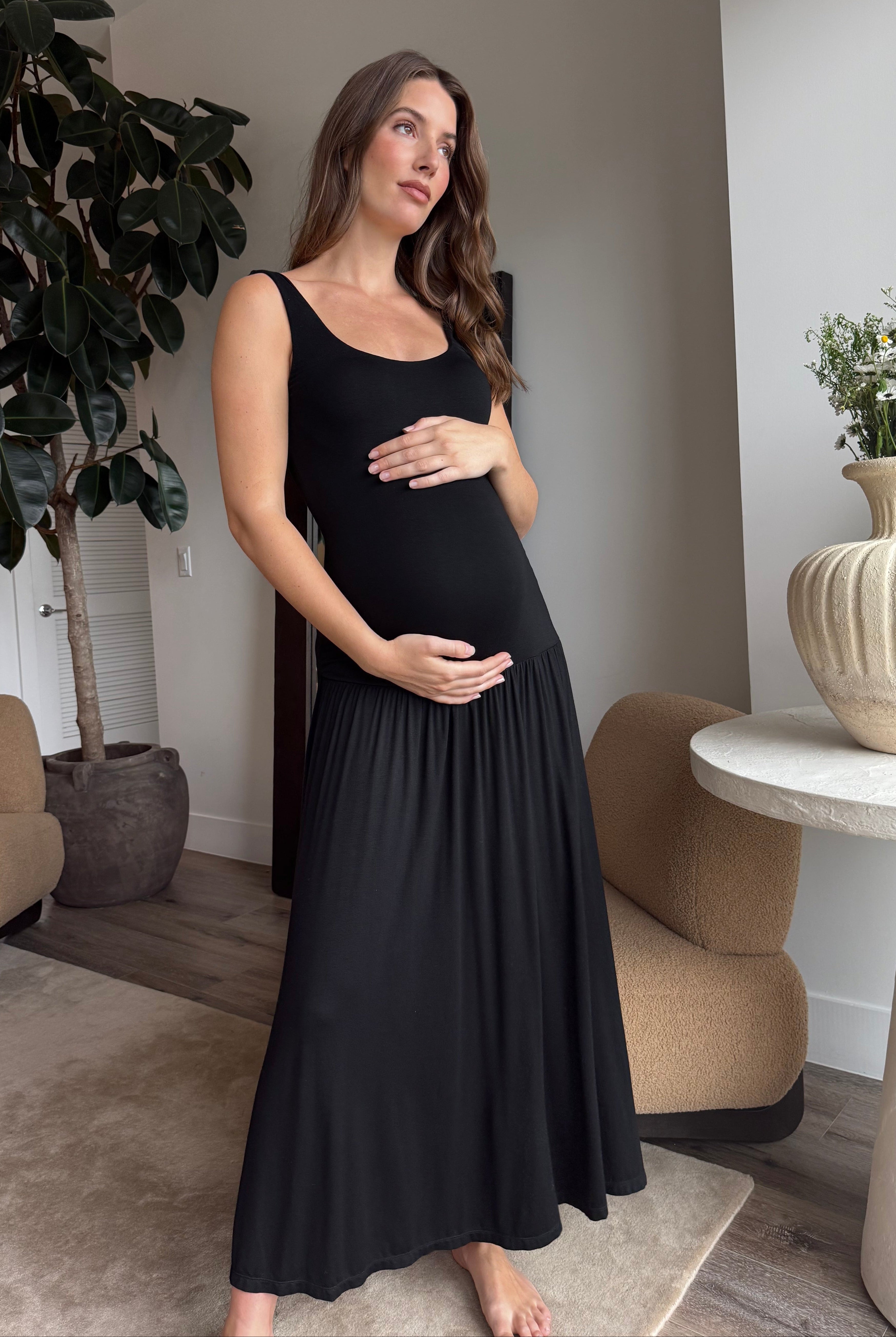 Pregnant woman in a black dress standing in a modern living room.