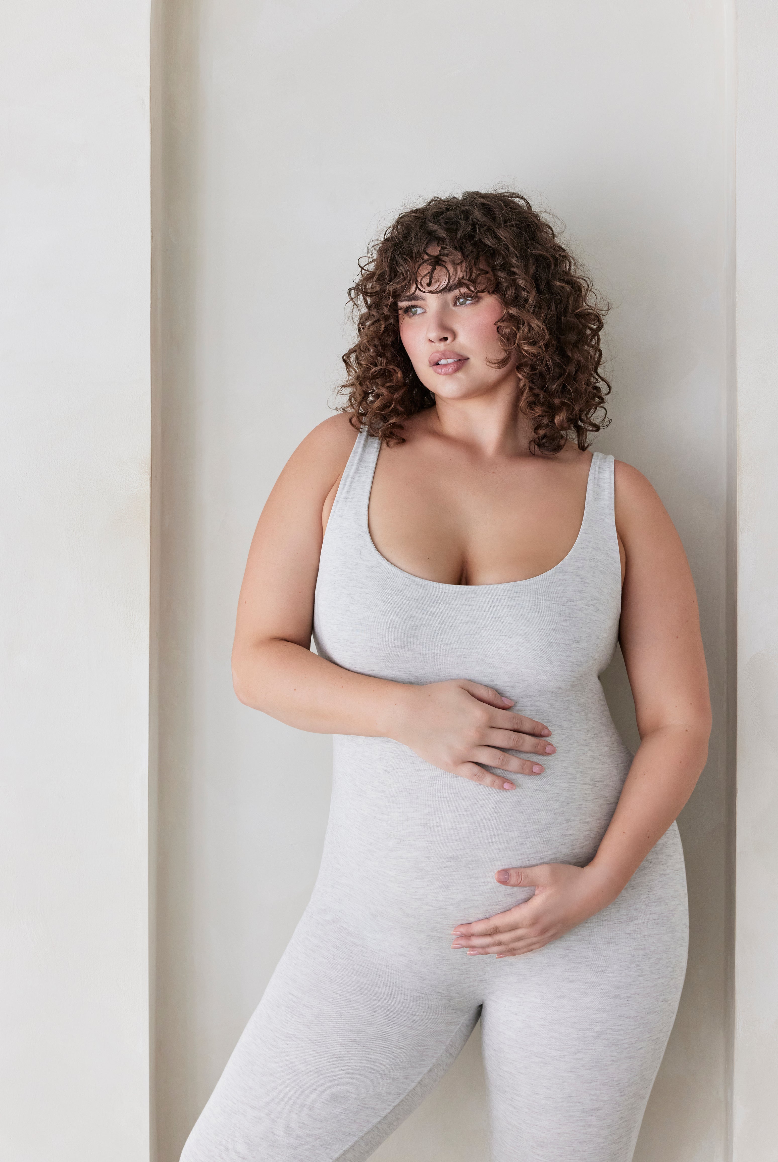 Woman wearing a grey bodysuit against a plain background