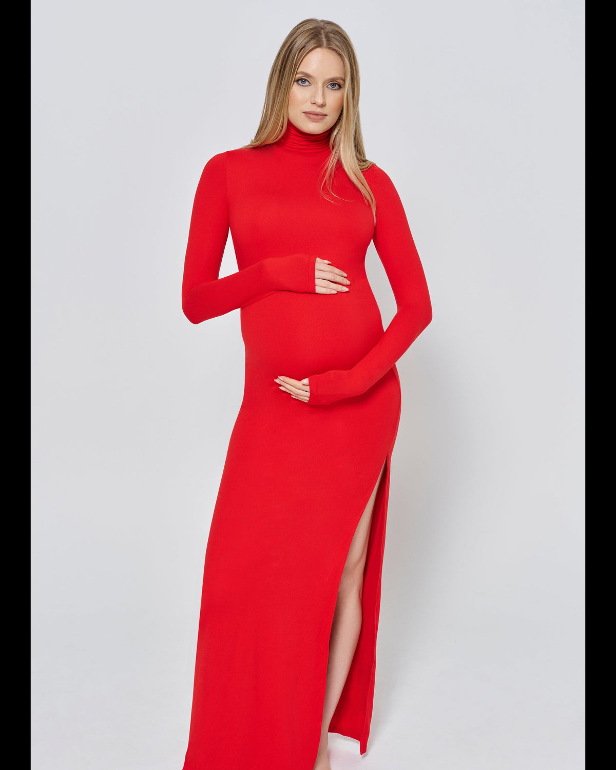 Woman wearing a red dress with a high slit on a light gray background