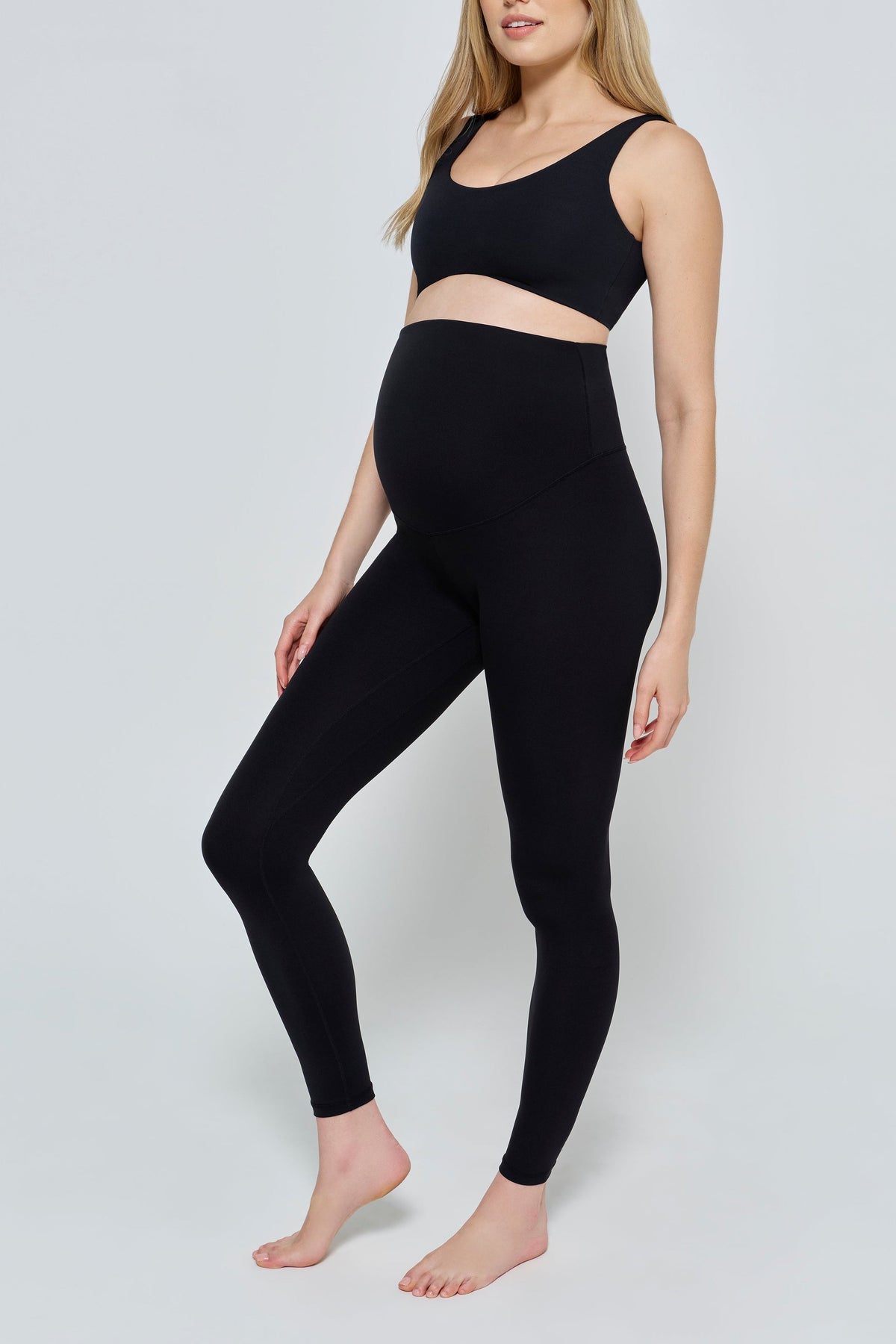 Front view of The Perfect Movement Maternity Legging showcasing its black full-length fit on a pregnant model against a light gray background