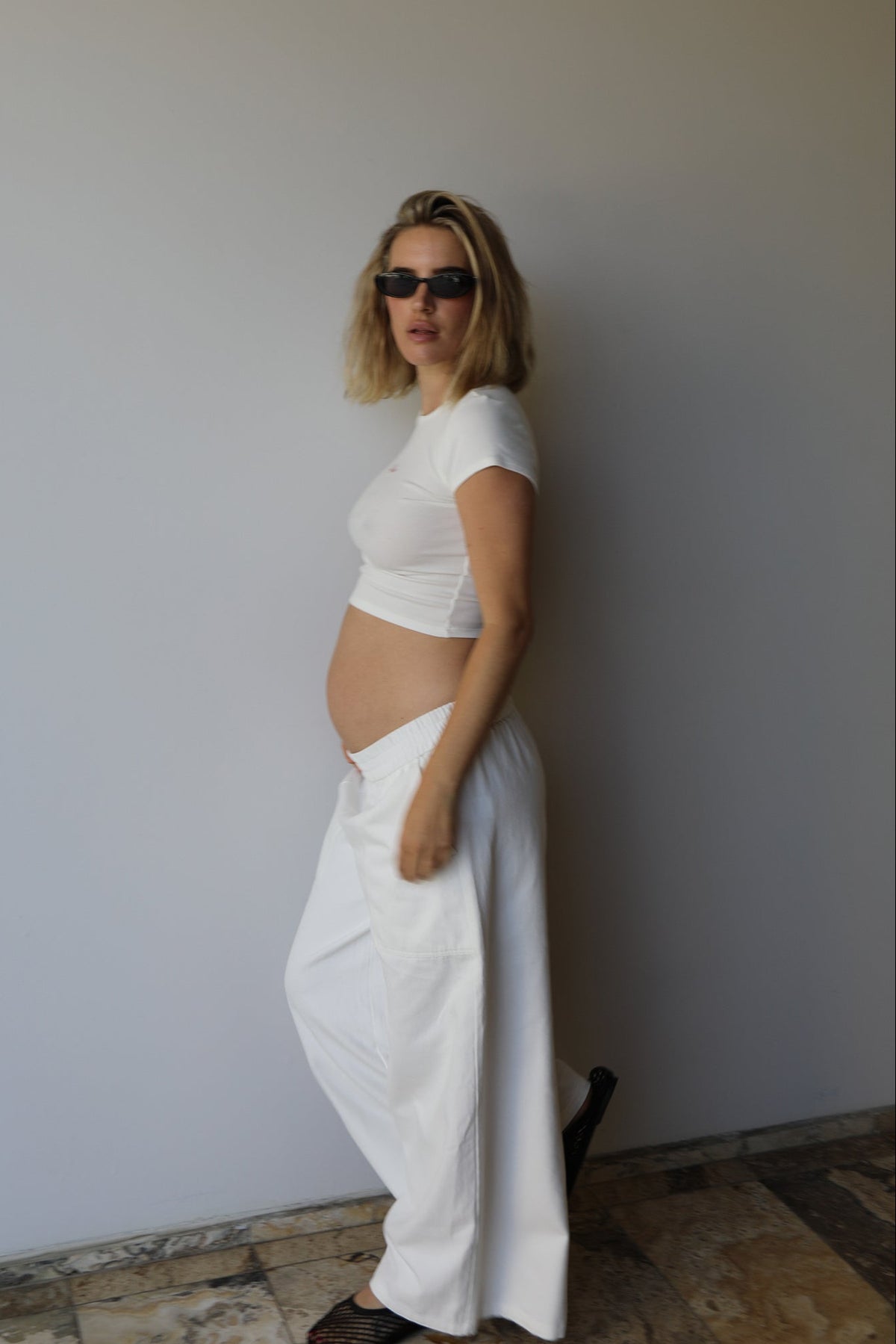 Side view of The Wide Leg Jean showcasing its elastic waist and relaxed fit on a pregnant model against a light gray wall