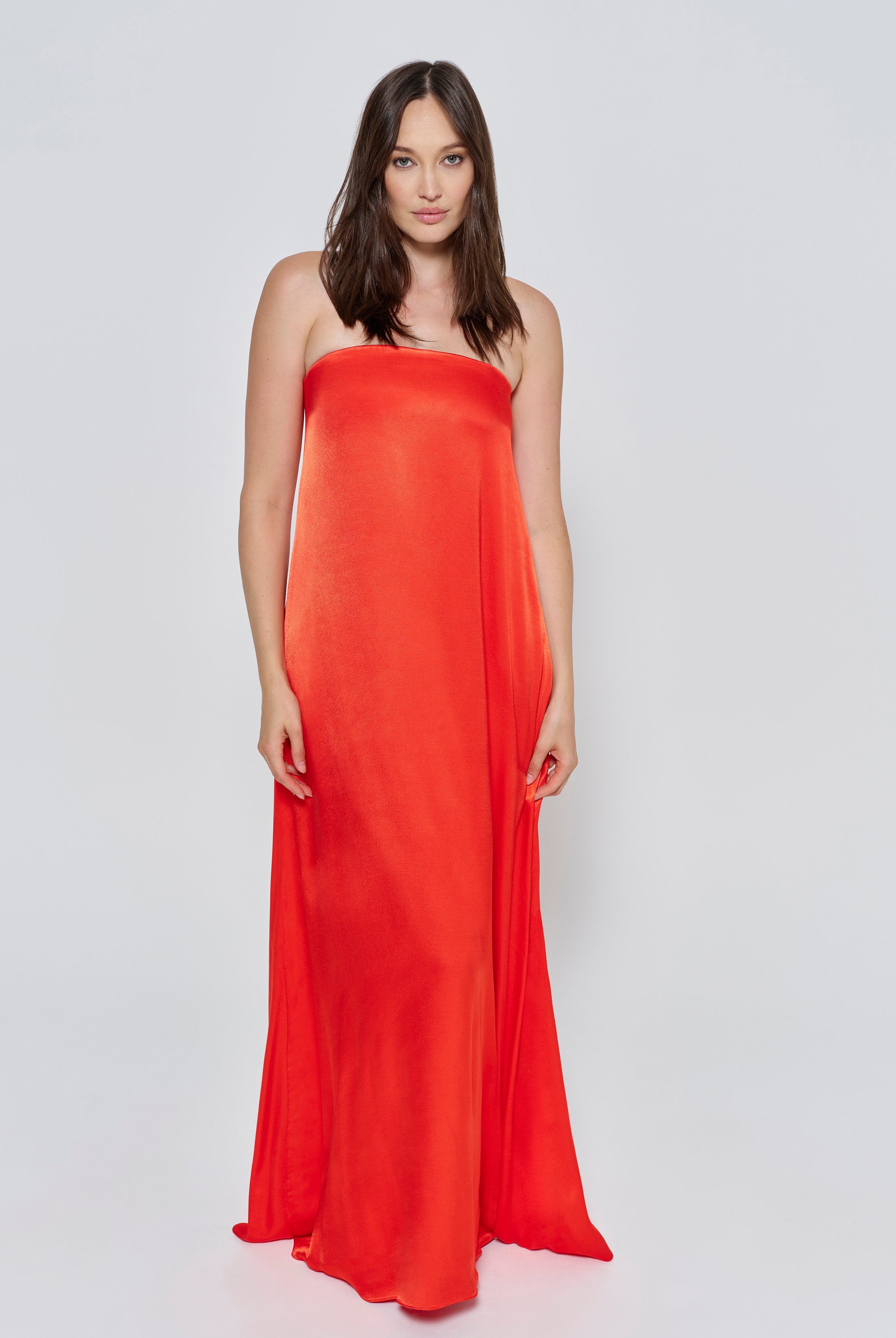 A woman wearing the Bumpsuit brushed satin strapless maxi maternity gown in red against a white background