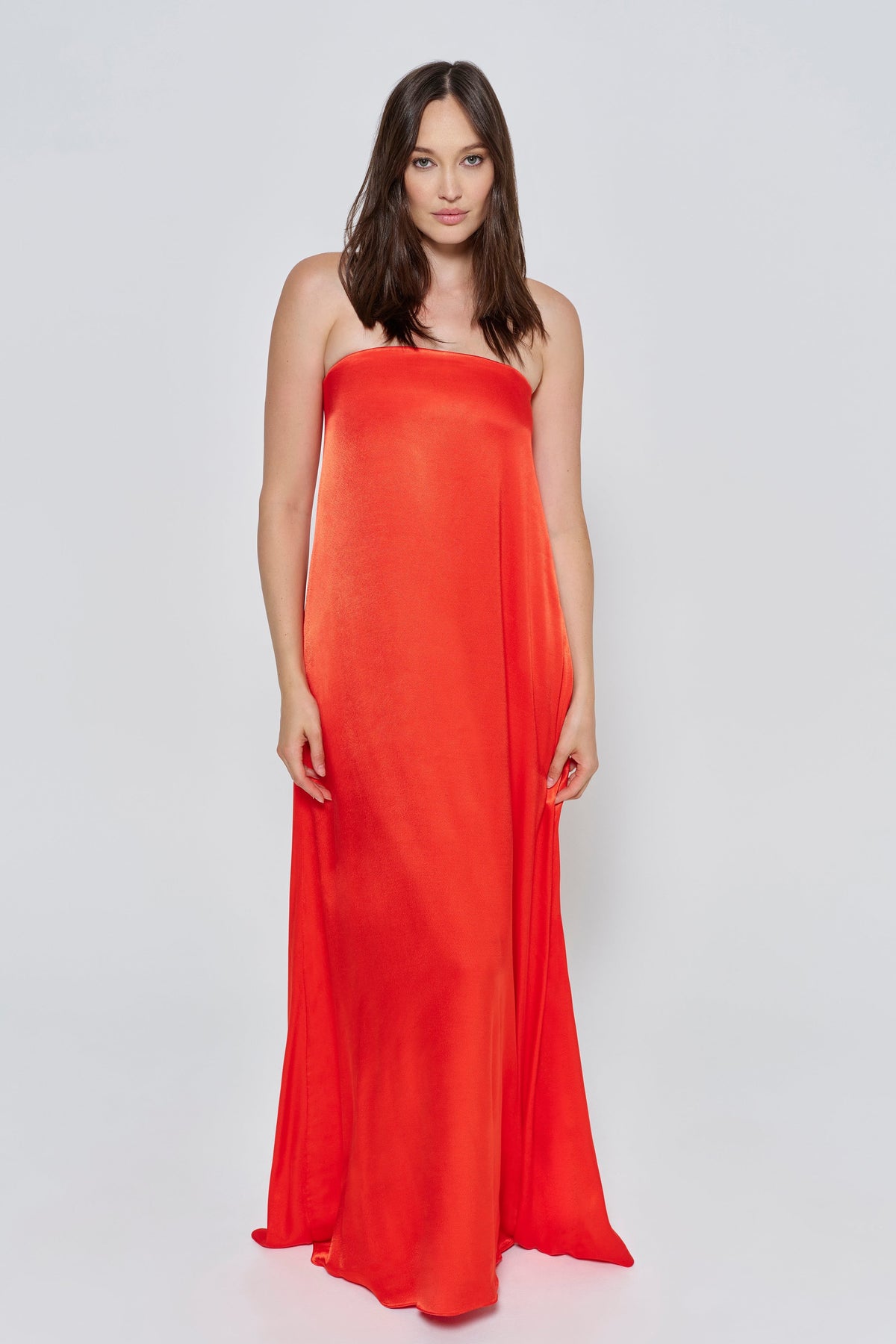 A woman wearing the Bumpsuit brushed satin strapless maxi maternity gown in red against a white background