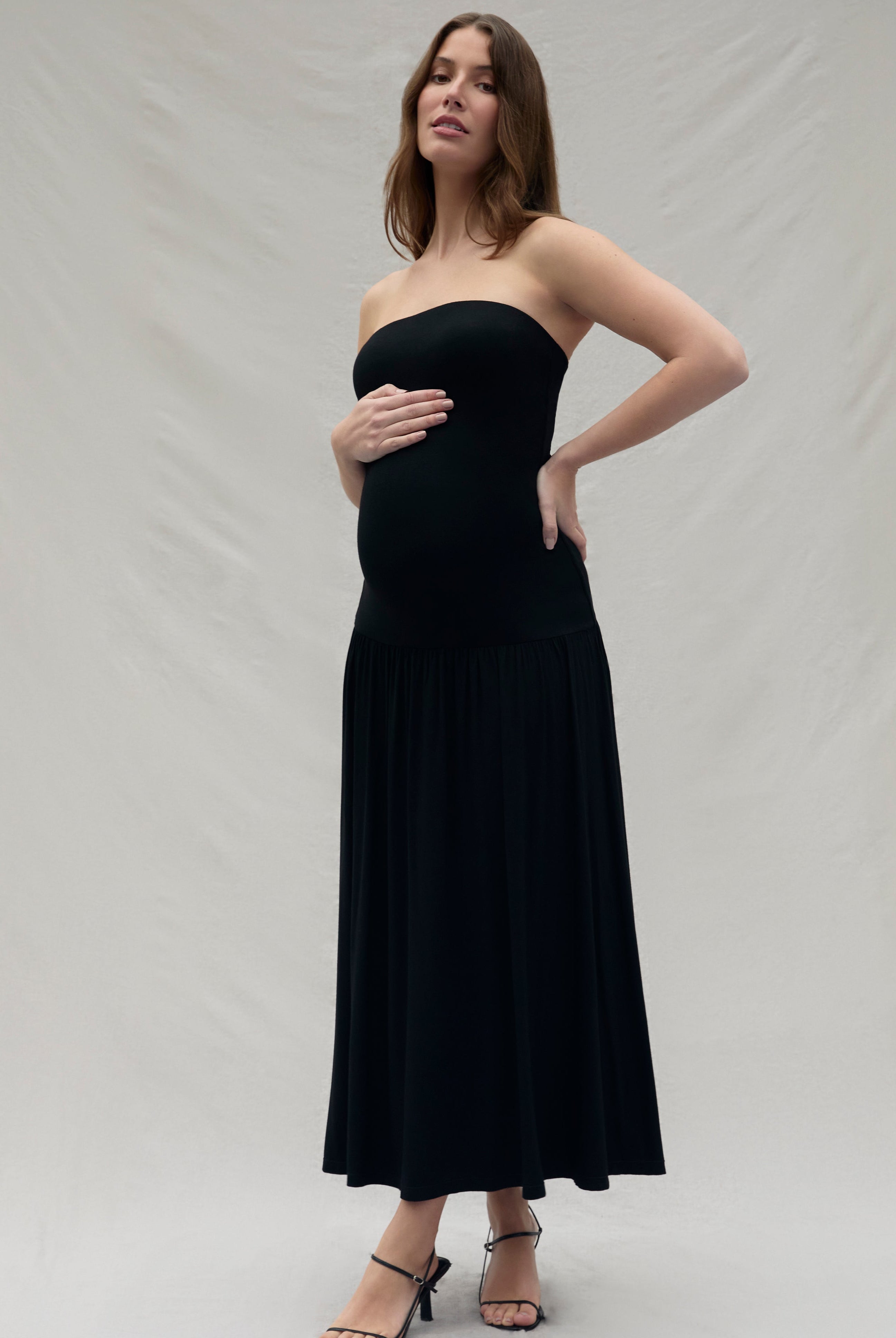 Woman wearing a black strapless dress against a plain background