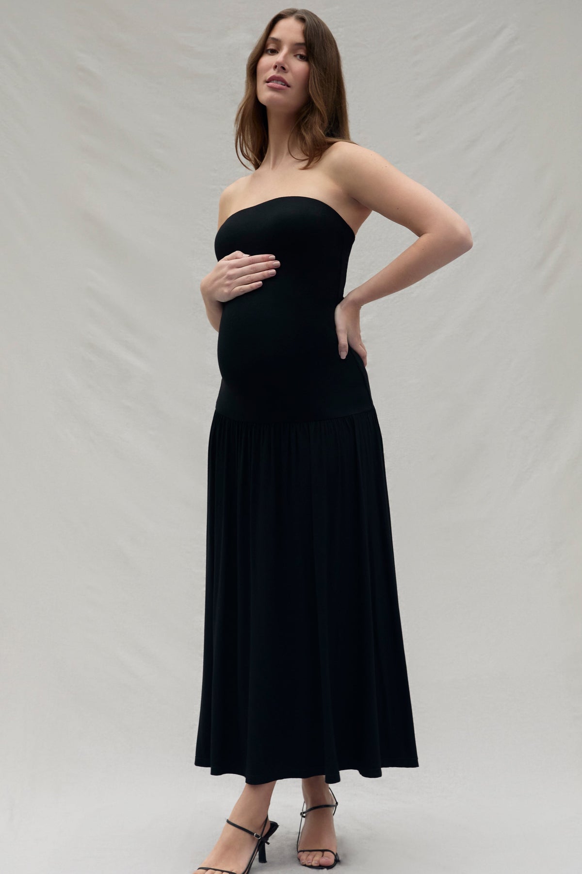 Woman wearing a black strapless dress against a plain background