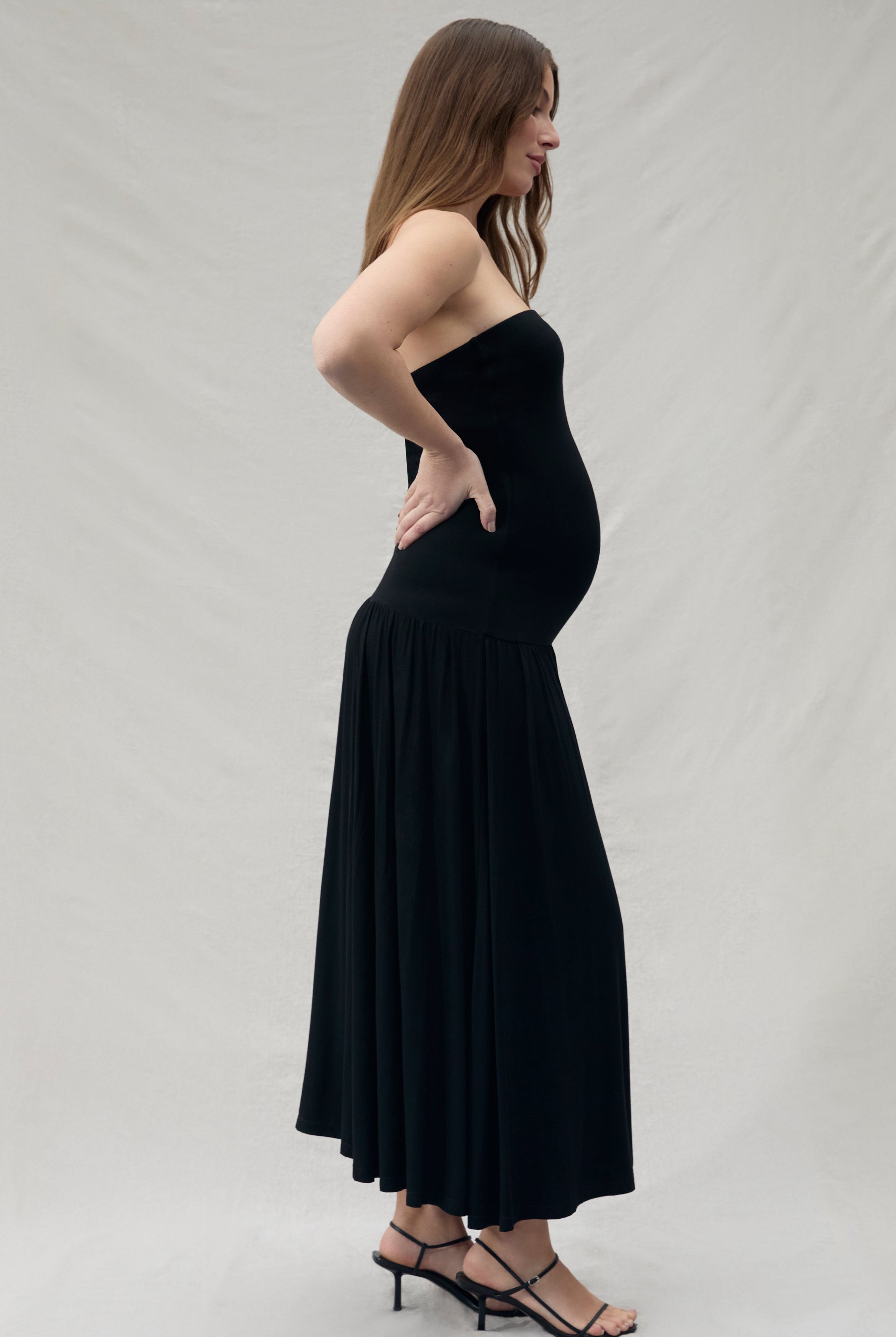 Woman wearing a black strapless dress against a plain background