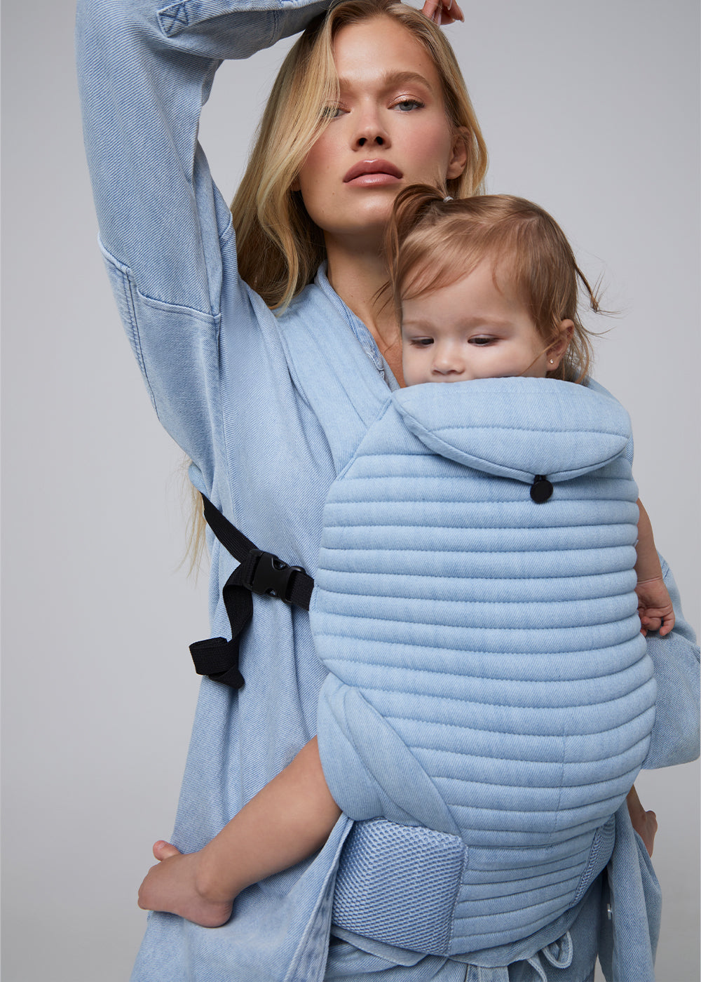 model wearing the armadillo baby carrier by bumpsuit in light denim