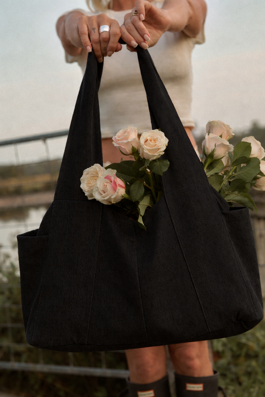 lady holding a black denim diaper bag with roses inside