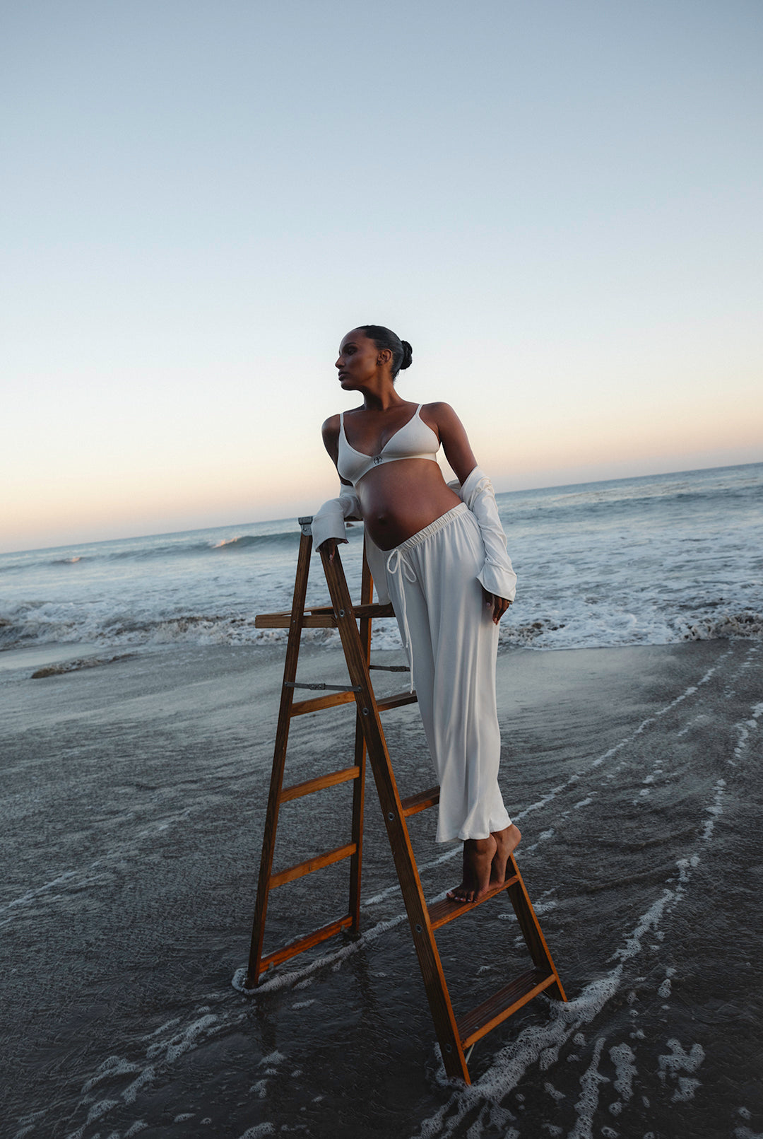 Person standing on a beach with a ladder, wearing a white Luxe pj set