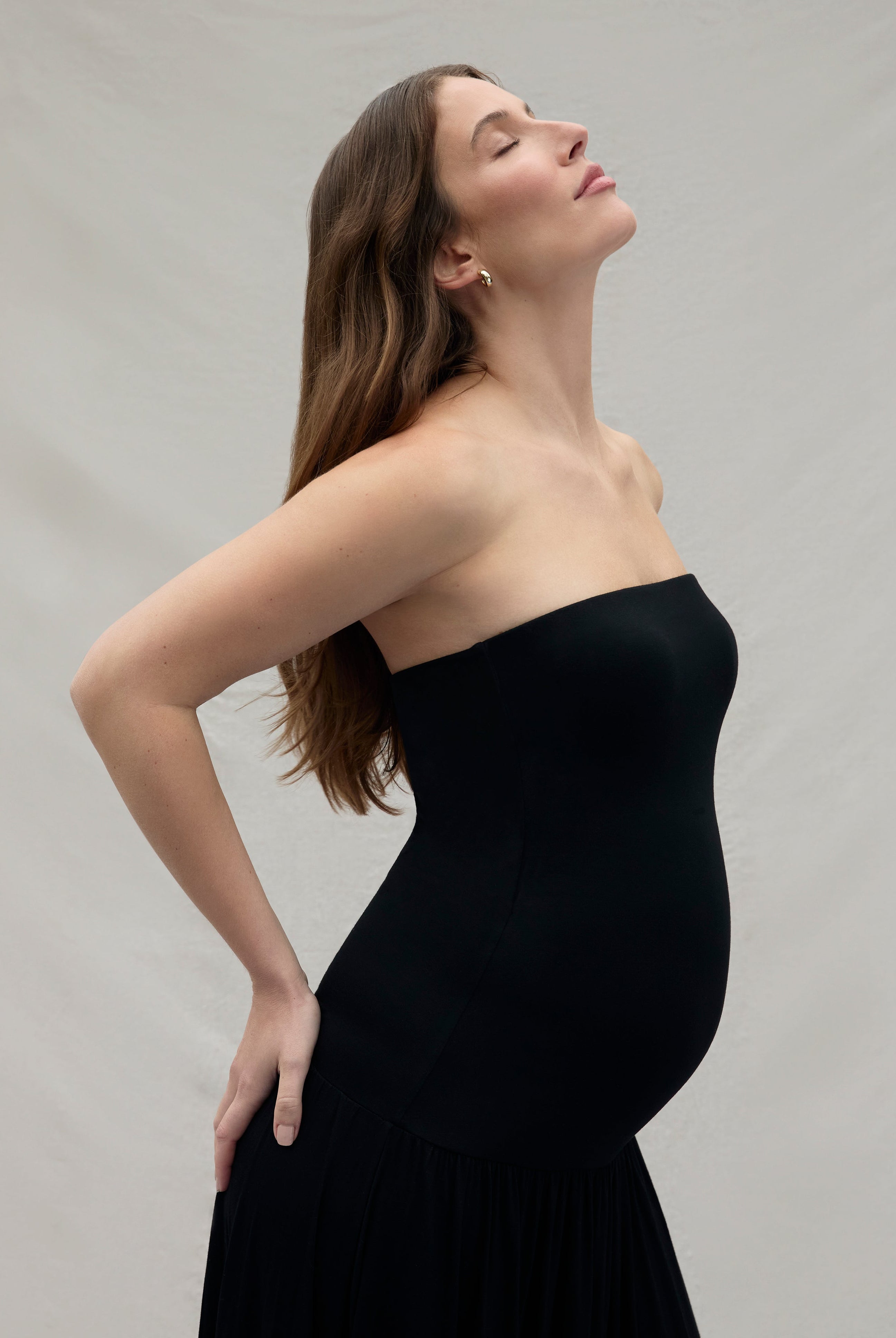 Woman wearing a black strapless dress against a plain background